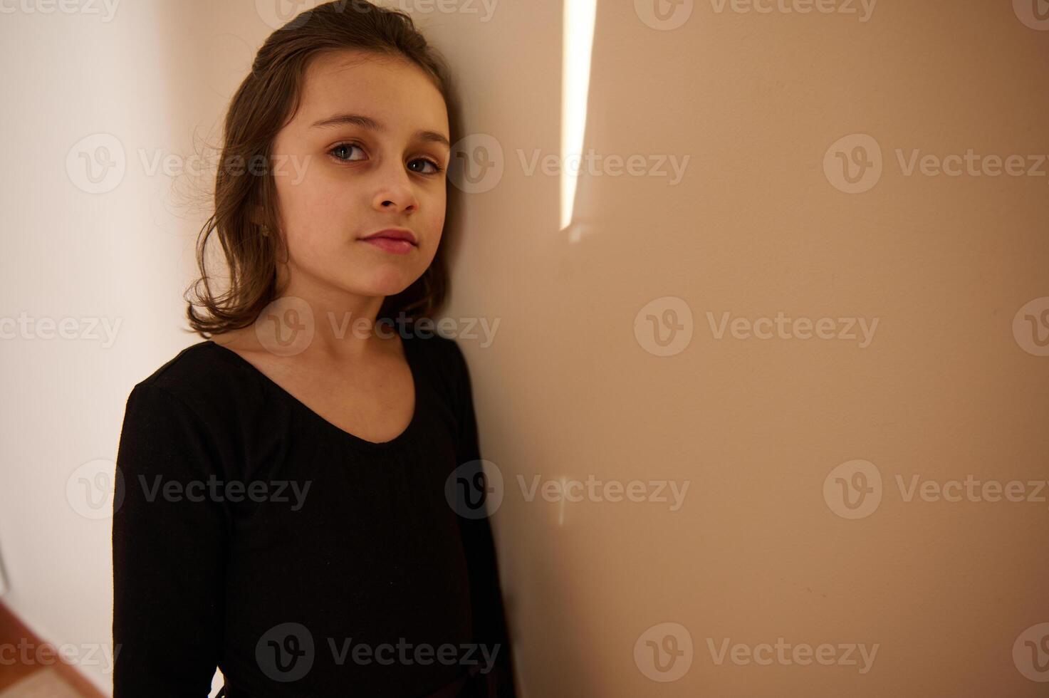 Portrait of a girl in black attire against a beige wall photo
