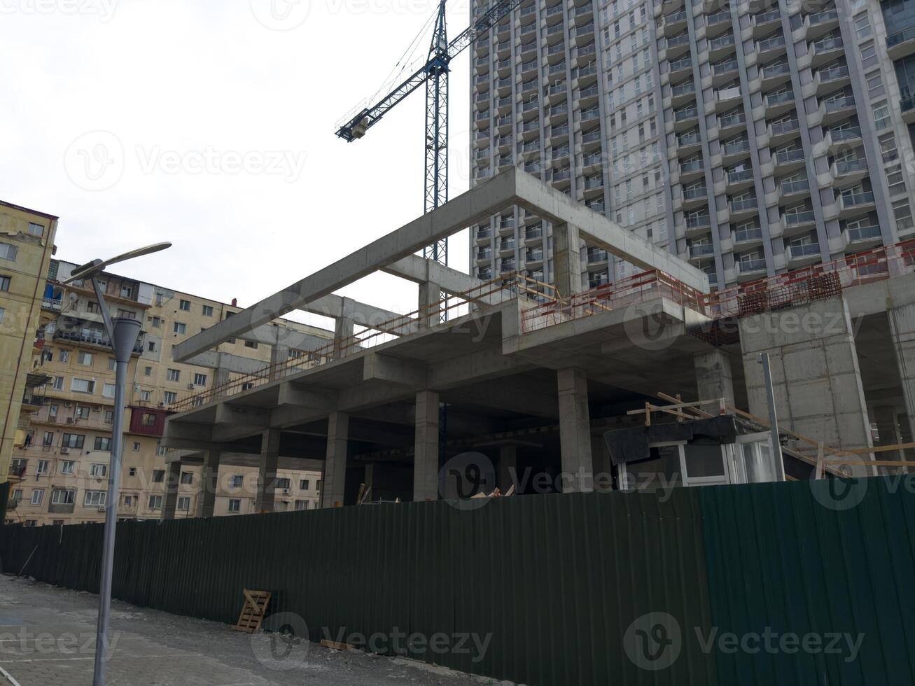 Construction crane and concrete frame outside the fenced construction area photo
