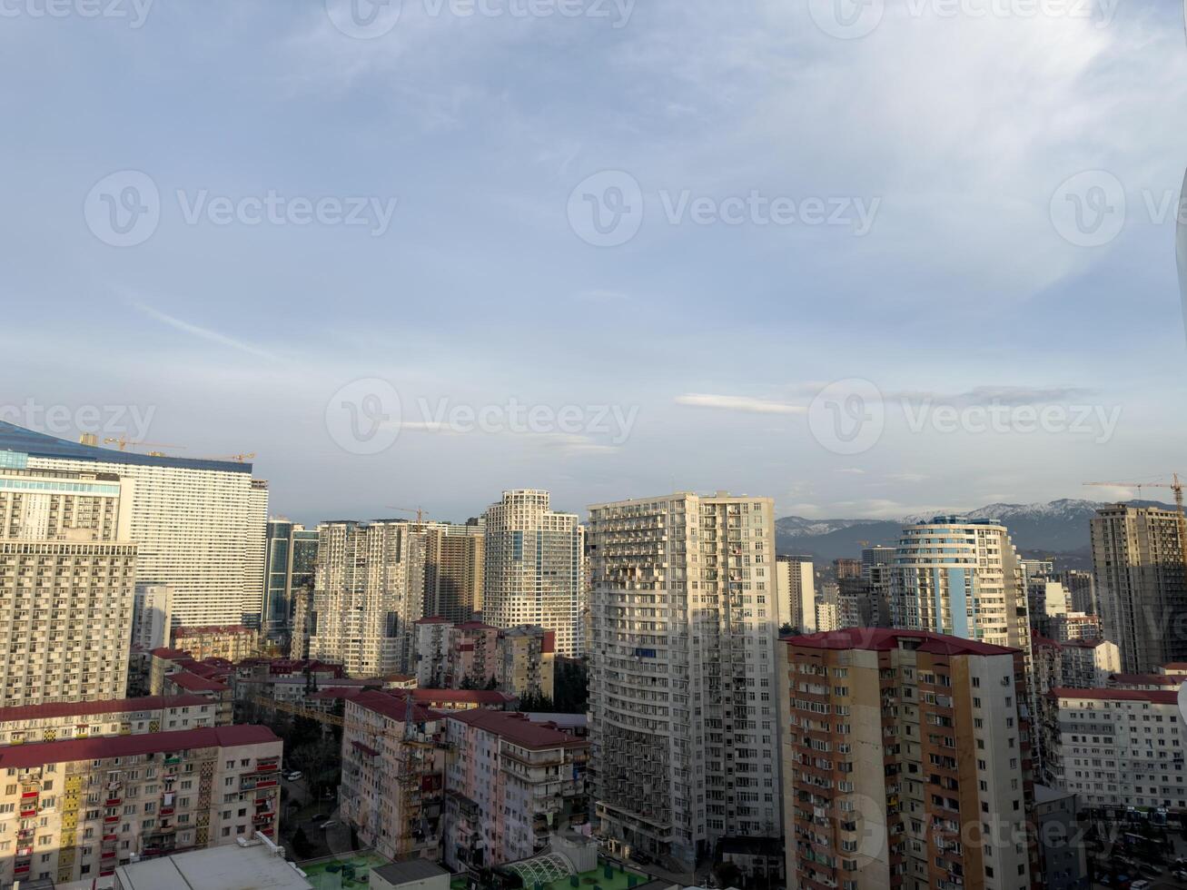 Cityscape of Batumi from high floor overlooking old district. Large residential area with tall houses and mountains in background in Georgia. Urban development with residential buildings photo