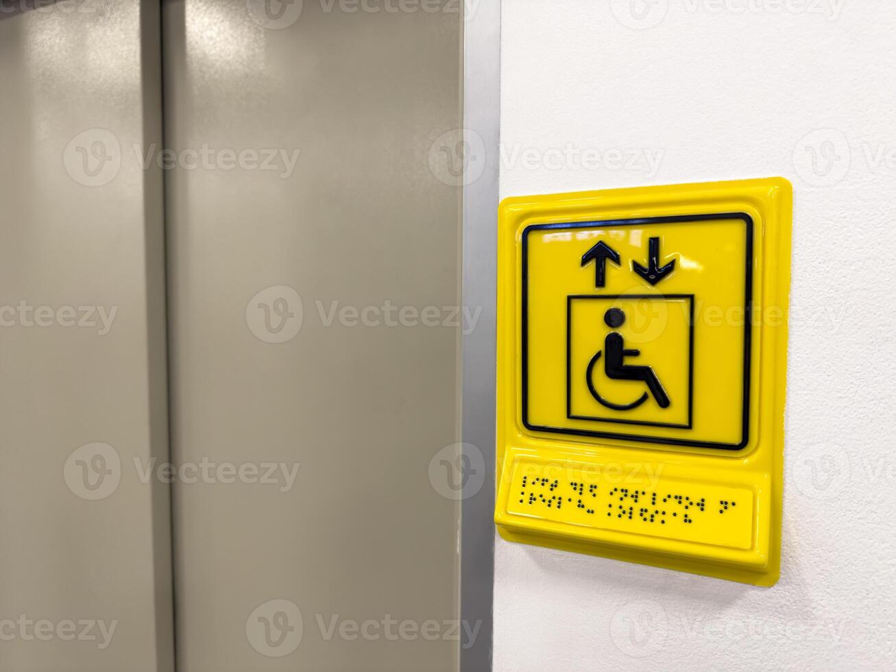 Sign indicating elevator for people with disabilities. Yellow sign with wheelchair and braille text to indicate elevator for blind people. Creating living conditions for people with disabilities photo