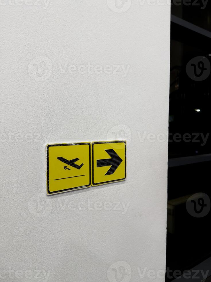 Sign with airplane symbol and arrow on wall indicating direction of departure of aircrafts at international airport. Assistance with orientation at airport, vertical photo