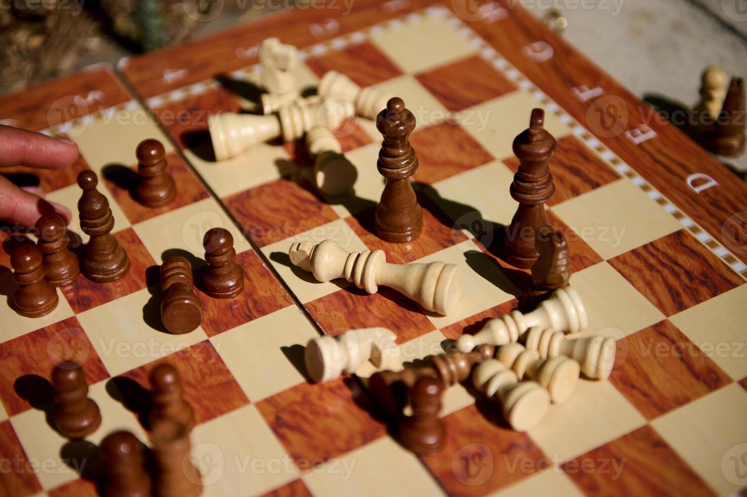 Chessboard with scattered pieces after an intense competitive match in bright sunlight photo