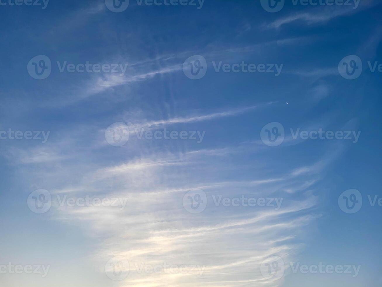 Strips of white fluffy clouds lie against the background of the blue sky photo