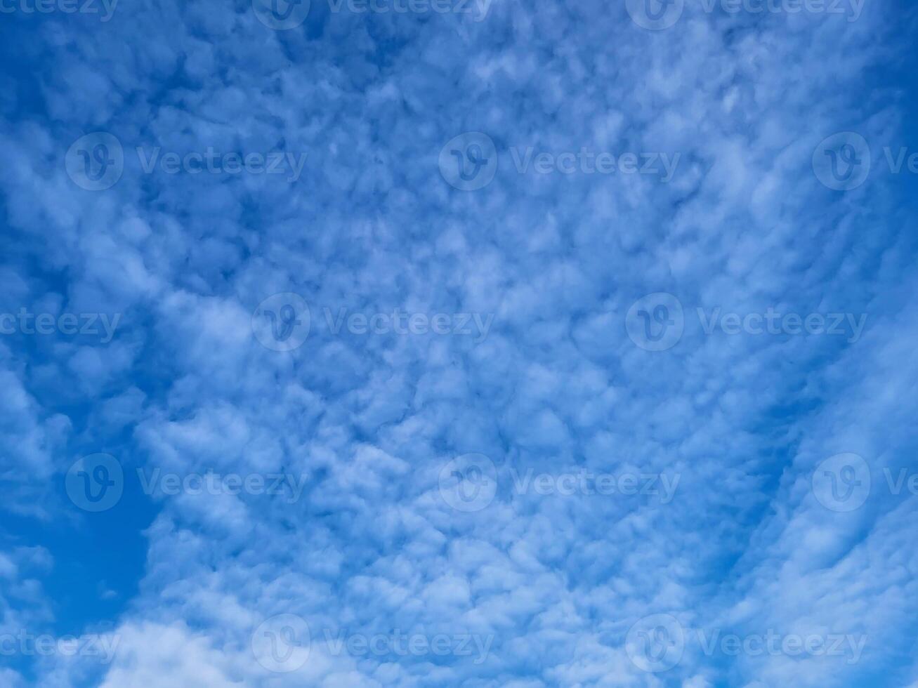 There are patches of small white clouds in the blue sky. A bright sunny summer day photo