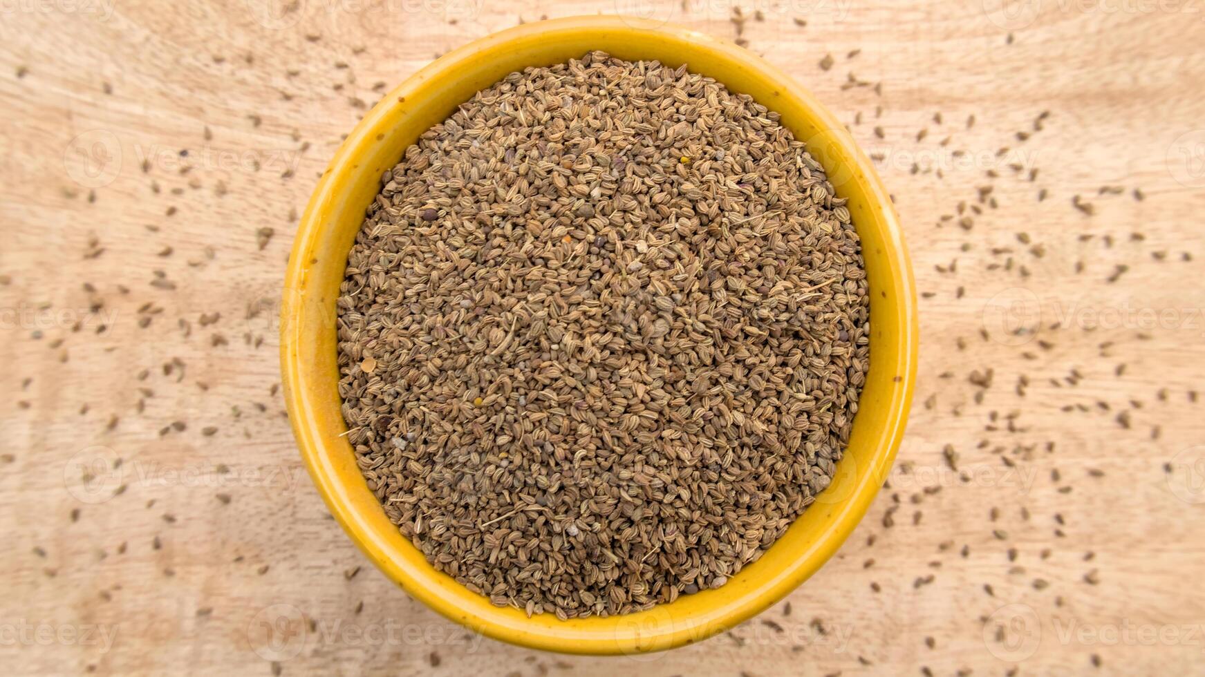 Carom Seeds, Thymol Seeds, Bishop's Weed, Ajwain in a Yellow Bowl, Flat Lay photo