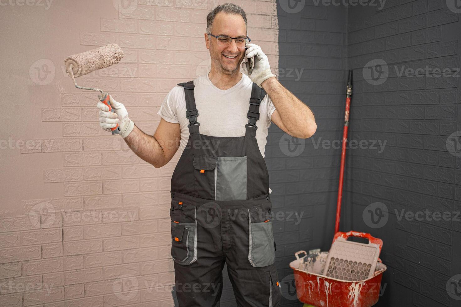 Smiling man holds a roller in his hand and makes a phone call photo