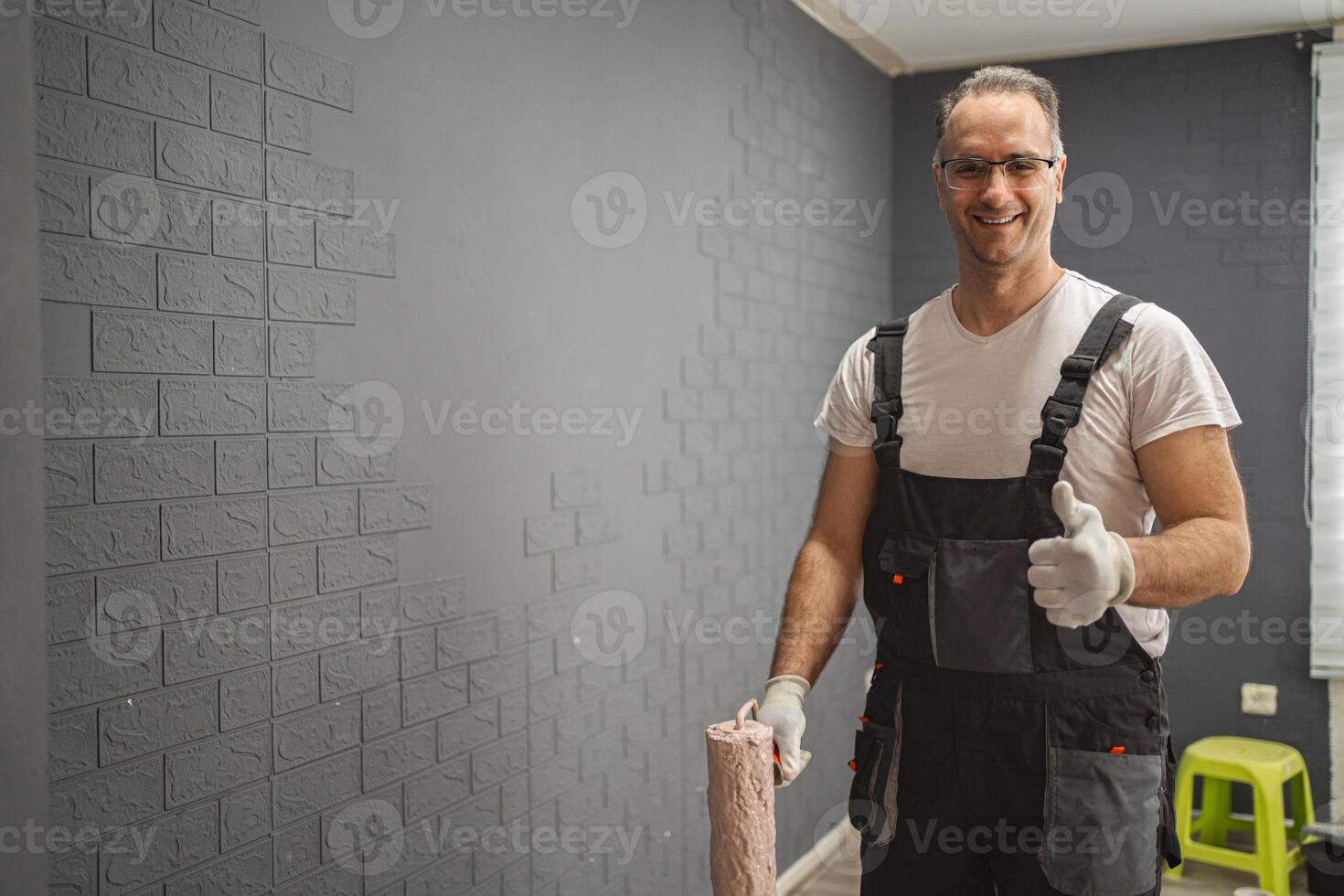 Smiling man with gloves and paint roller in hand photo