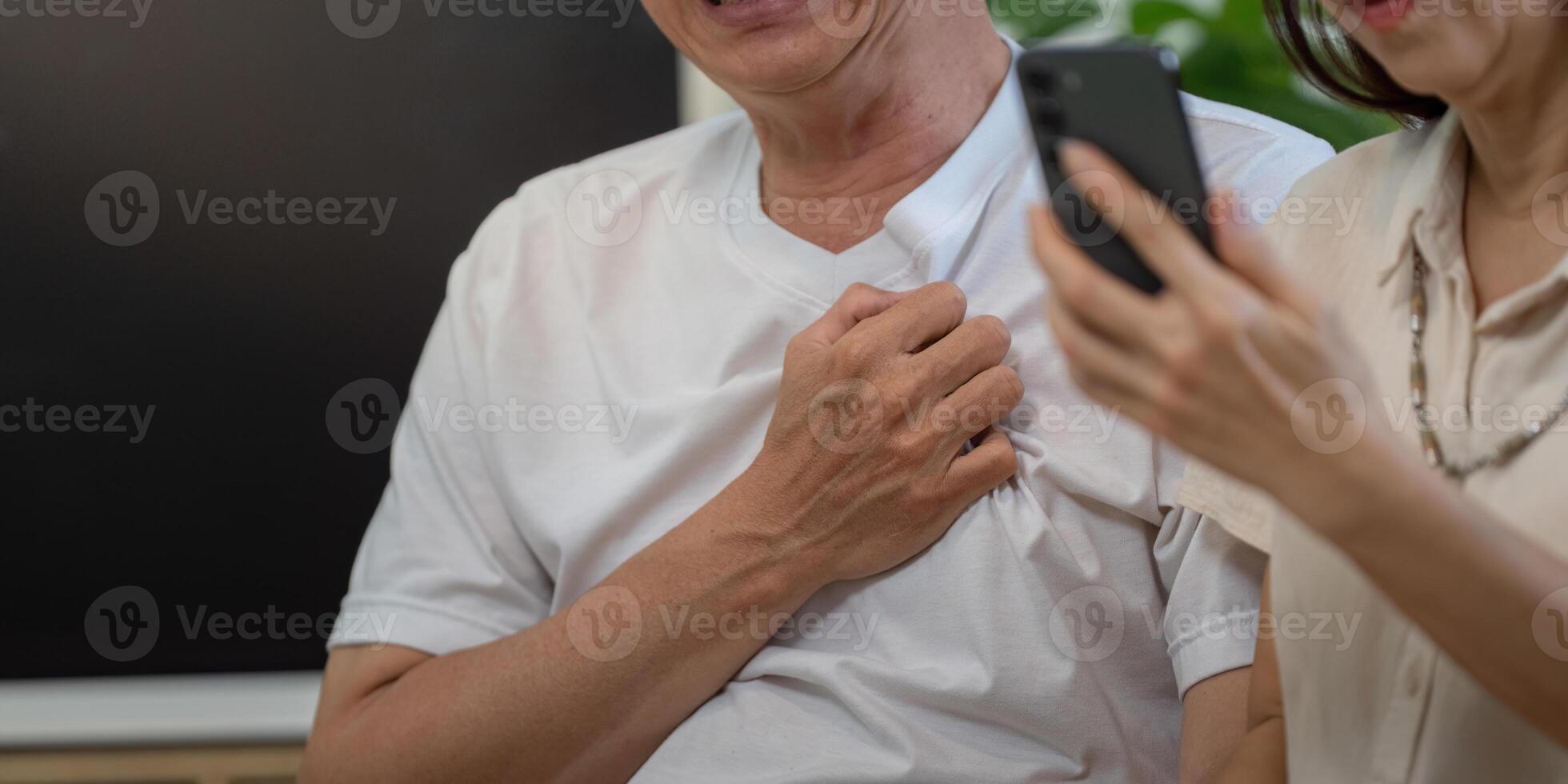 Elderly man smiling while holding his chest, woman on phone in supportive role. photo