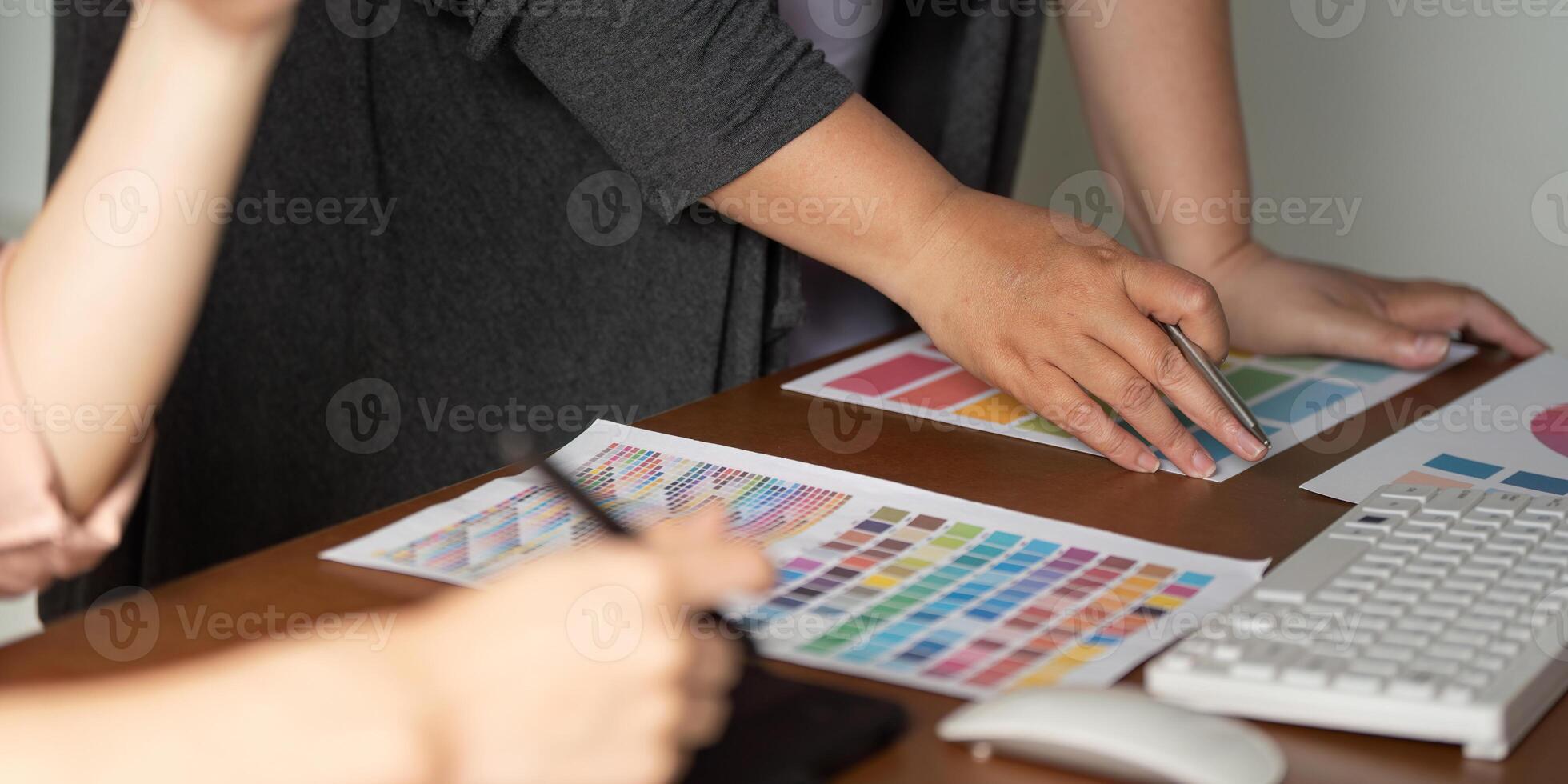 Diverse graphic design team analyzing color samples and prototypes at a table. photo