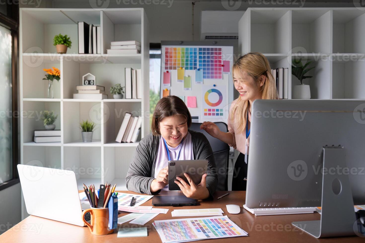 Diverse graphic design team sharing ideas and laughing while using a tablet. photo