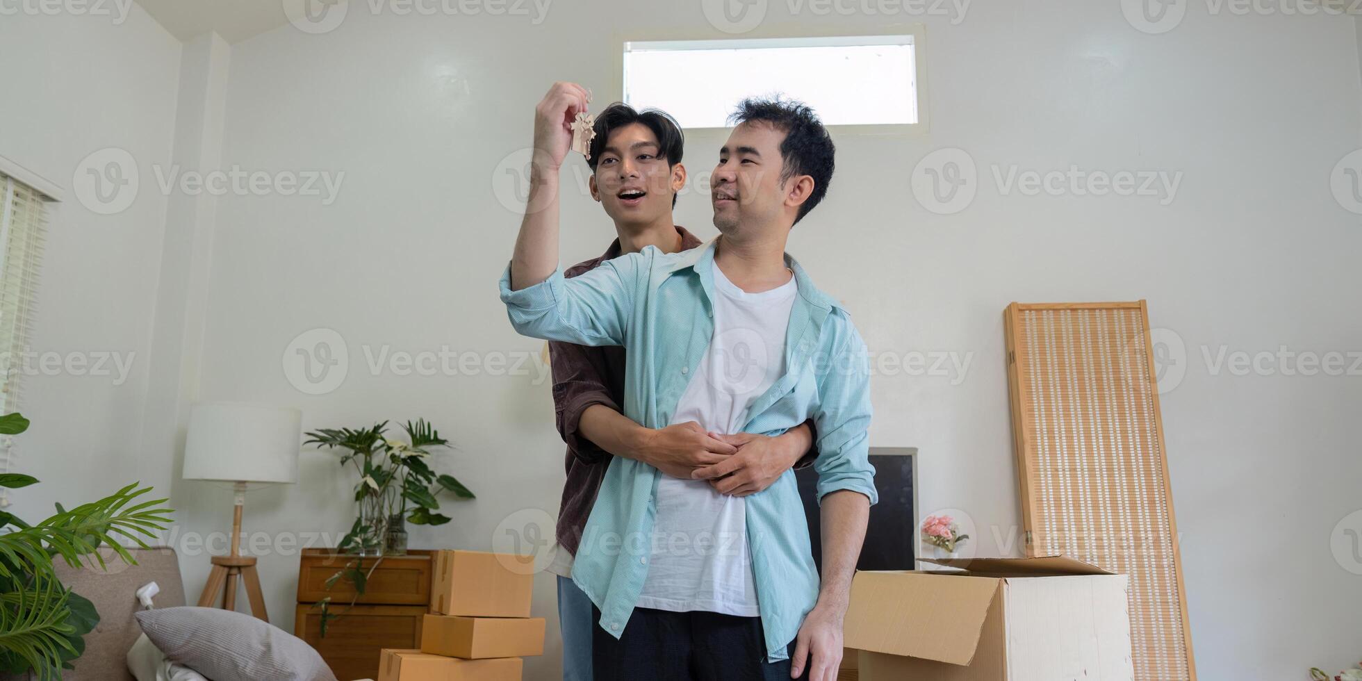 Gay couple celebrating with keys in their new home, expressing joy. photo