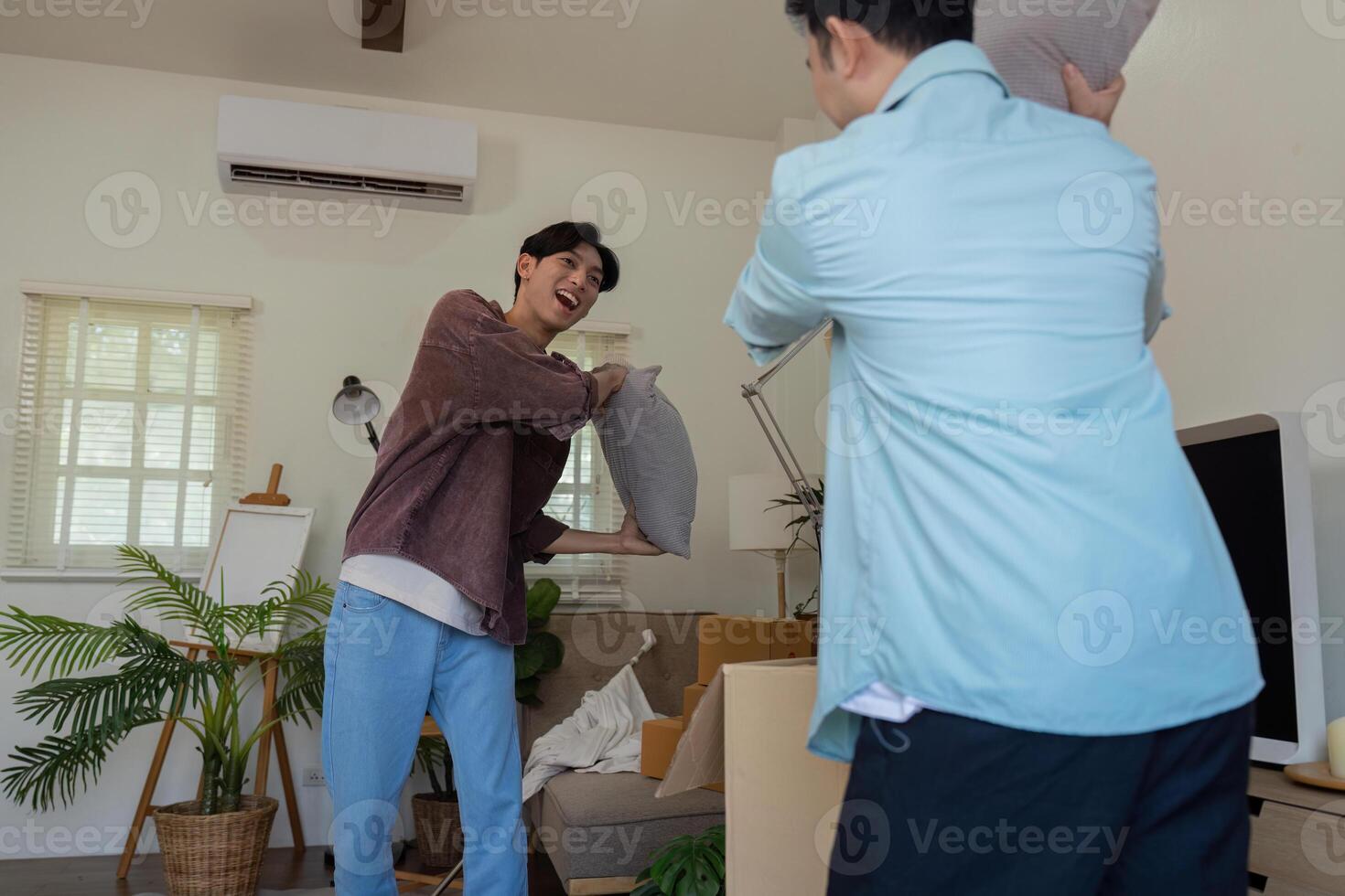 Gay couple playfully throwing pillows during unpacking in their new home. photo