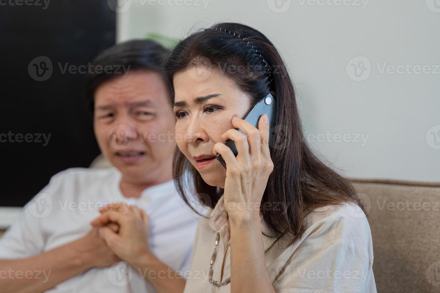 Worried woman on the phone while comforting elderly man with heartache. photo