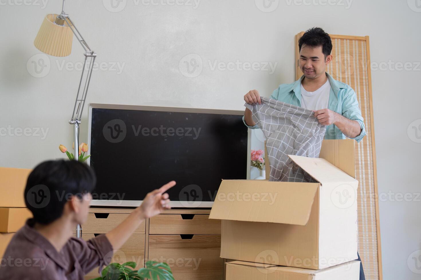 Gay couple organizing their new home, discussing items while unpacking. photo