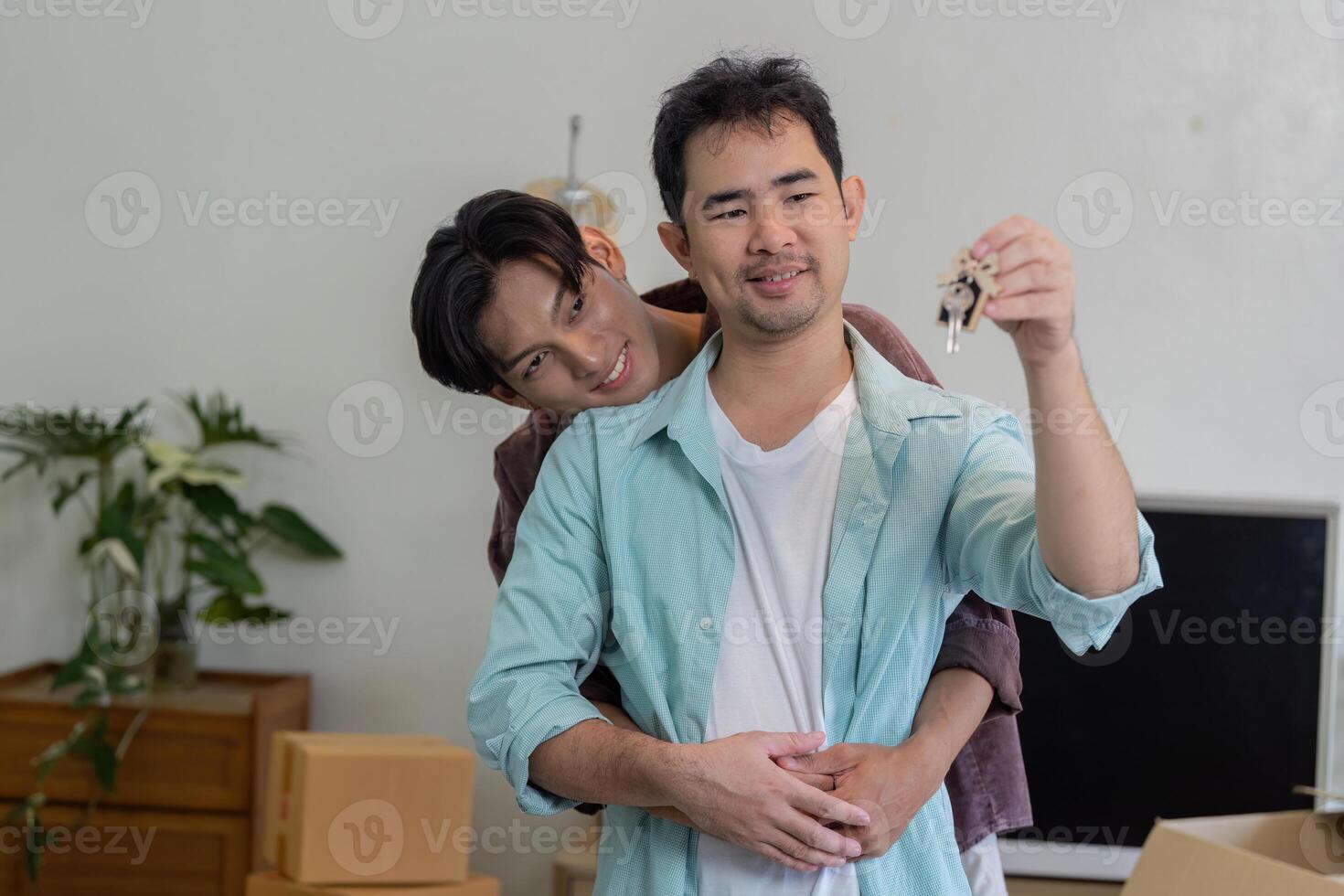 Gay couple celebrating new home, holding house keys together. photo