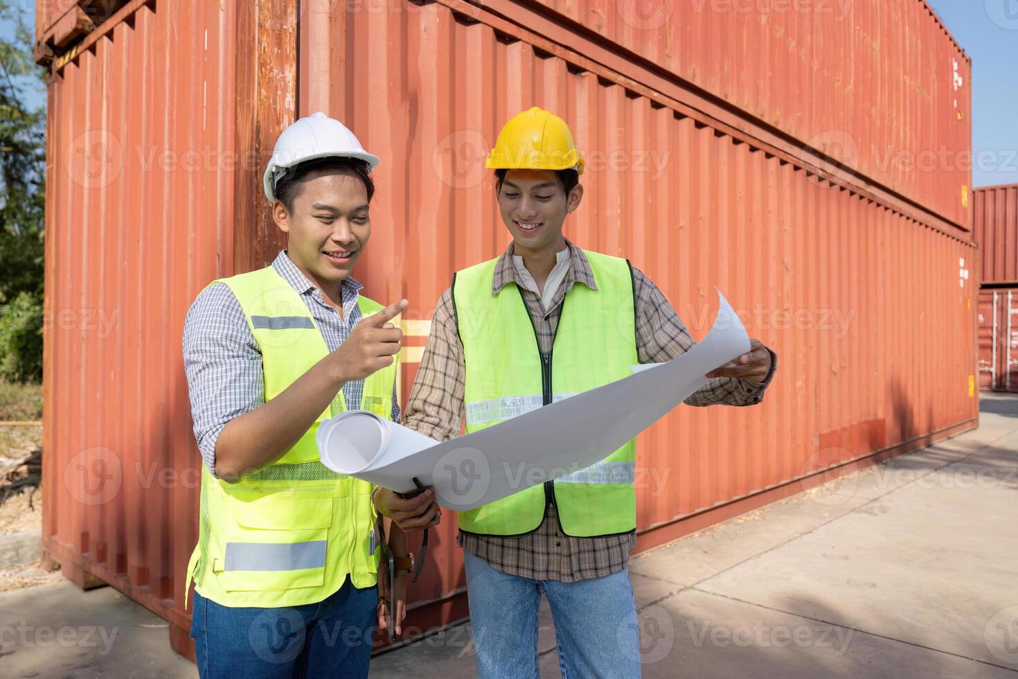 Engineers discussing logistics and reviewing plans at a shipping container facility photo