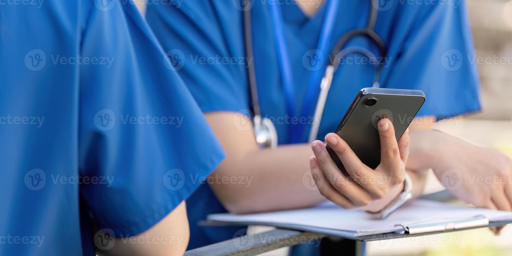 Doctors on a break, using a smartphone and reviewing notes. photo