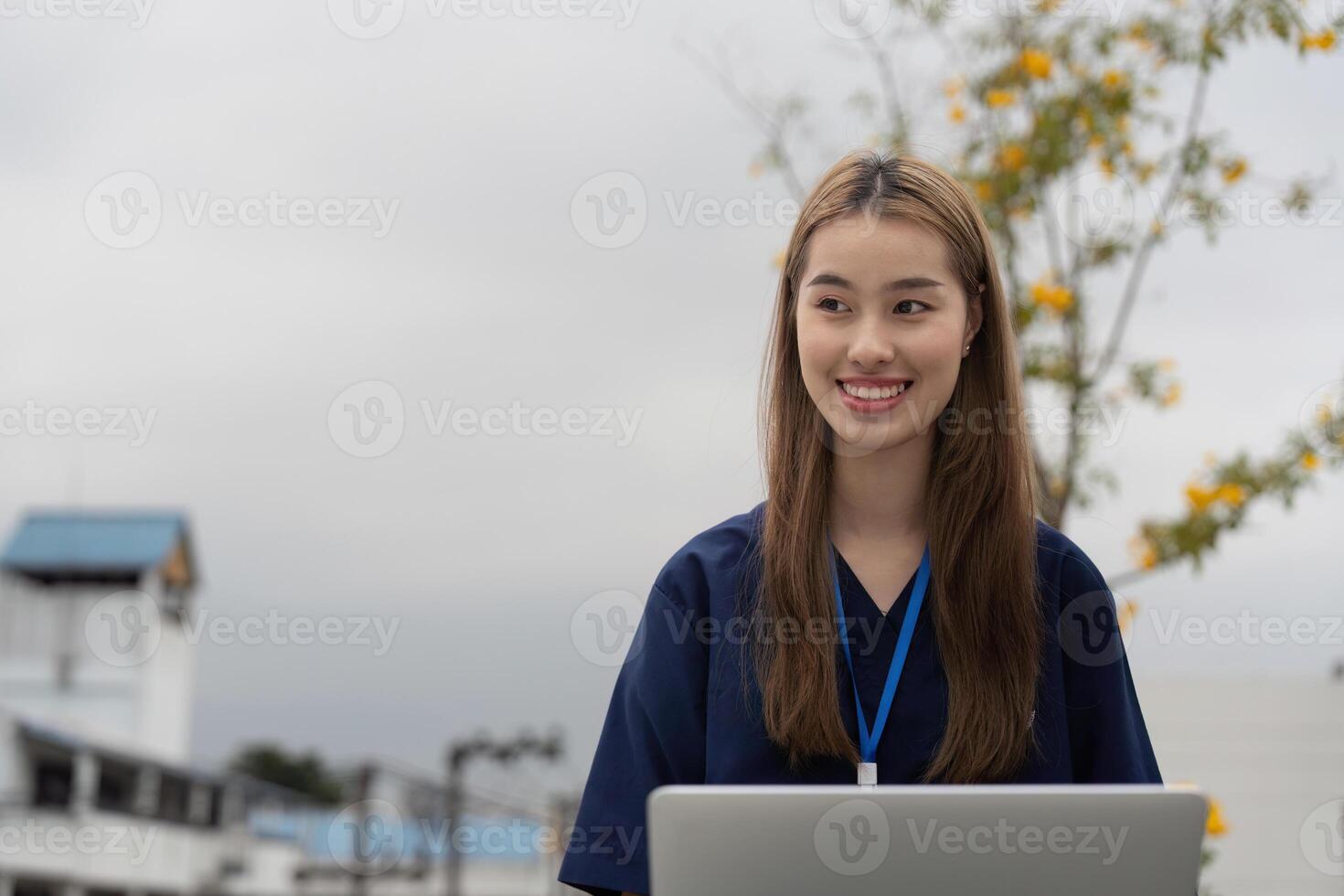 Nurse smiling while using a laptop for patient care and documentation during a break photo
