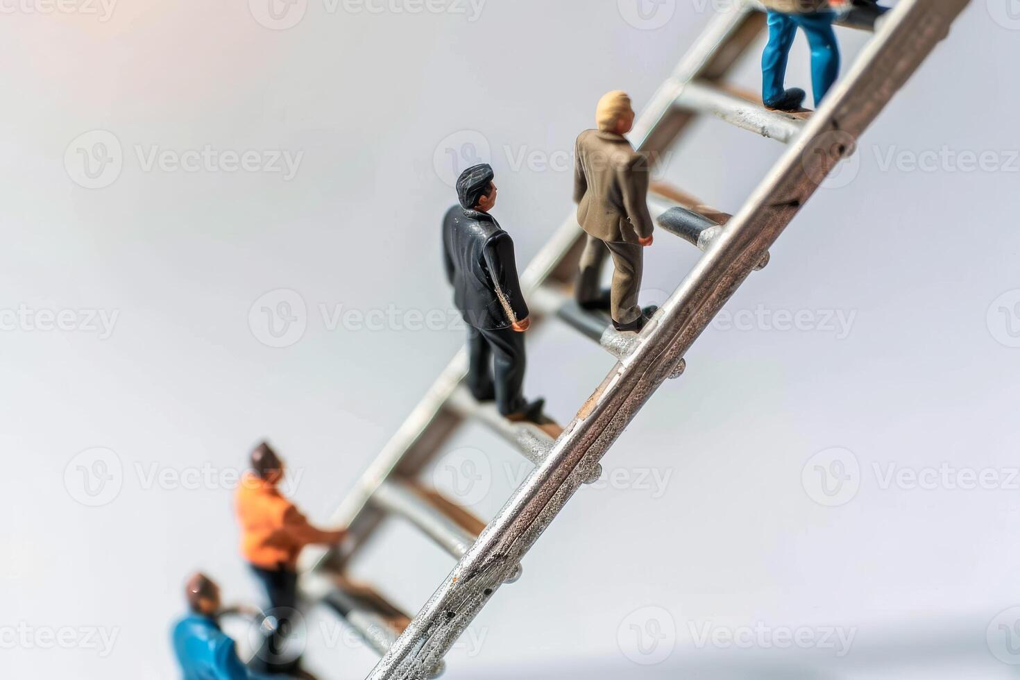 Miniature figurines ascend a silver ladder, representing the journey of climbing towards success and the challenges of personal and professional development photo