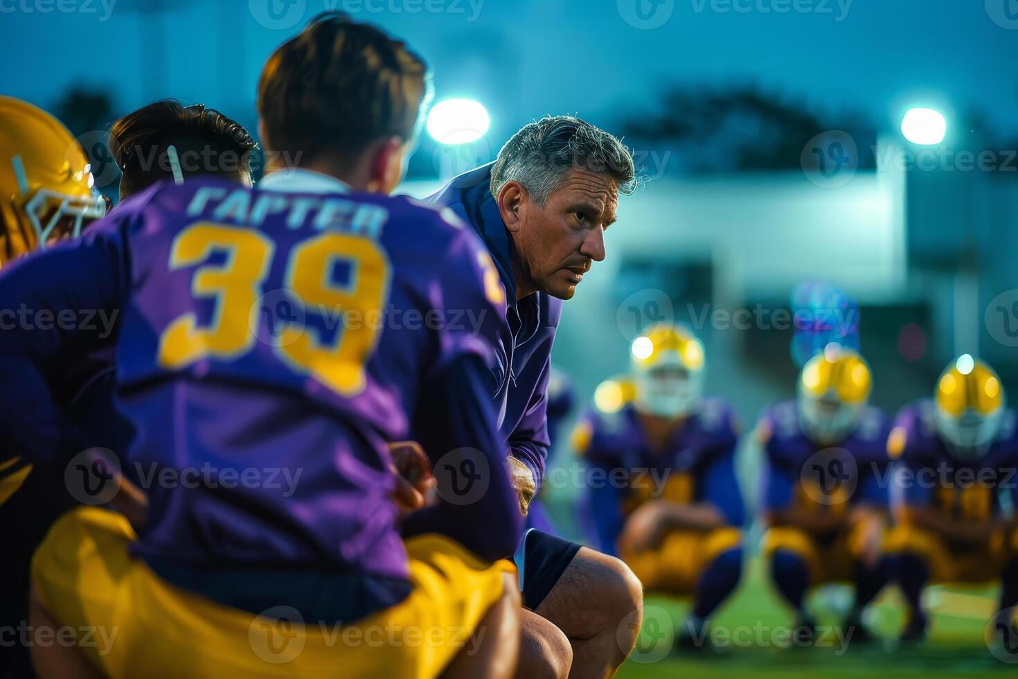 A coach sitting on the sidelines with his team photo