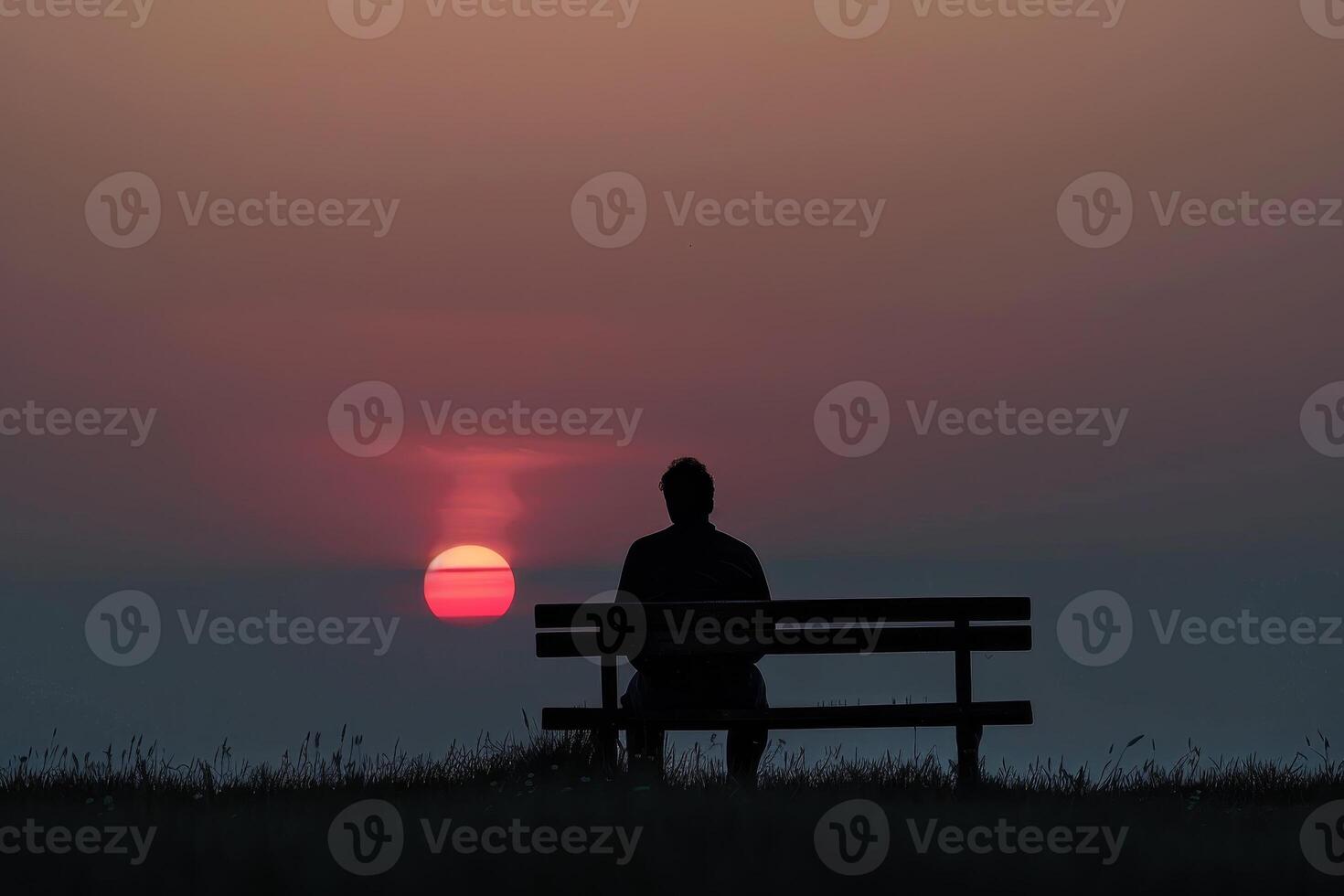 A person sitting on a bench at sunset photo
