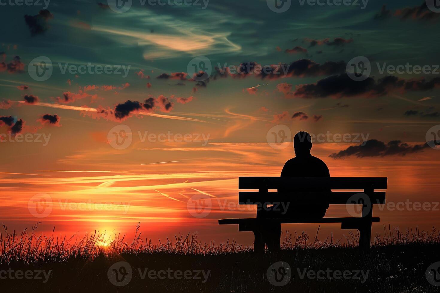 A man sitting on a bench at sunset photo