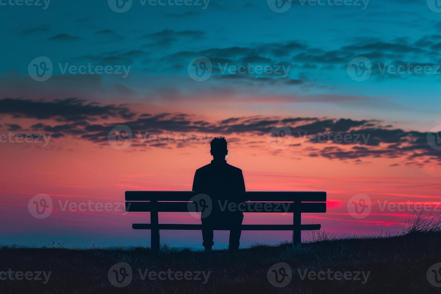 Man sitting on bench at sunset photo