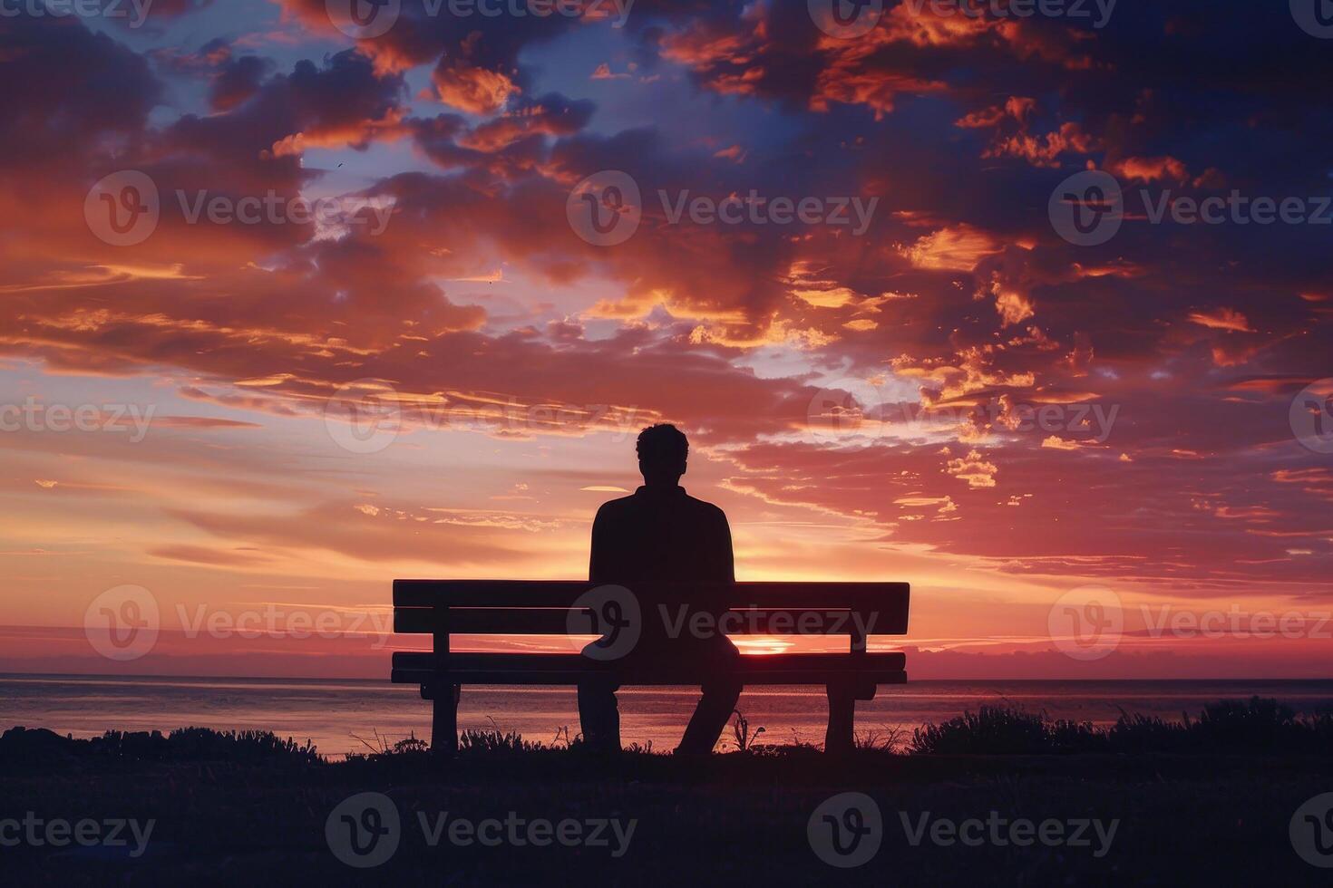 A man sitting on a bench at sunset photo