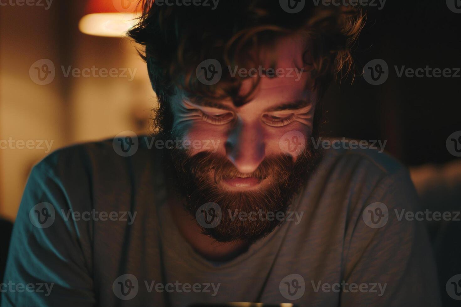 A man with a beard and a smile looking at his phone photo