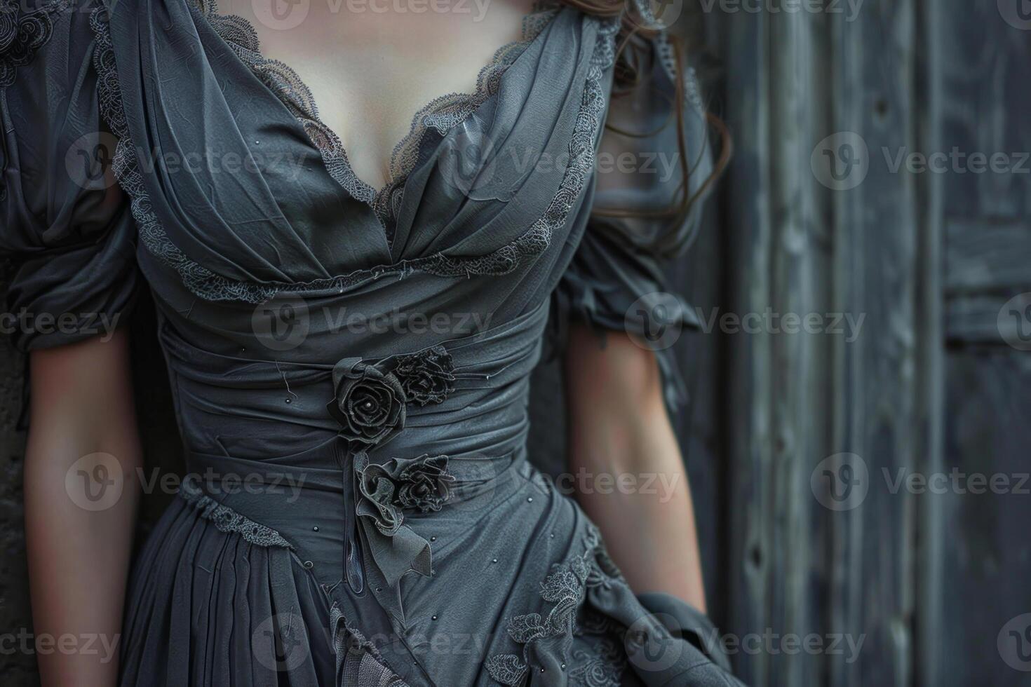 A woman in a gray dress leaning against a wall photo