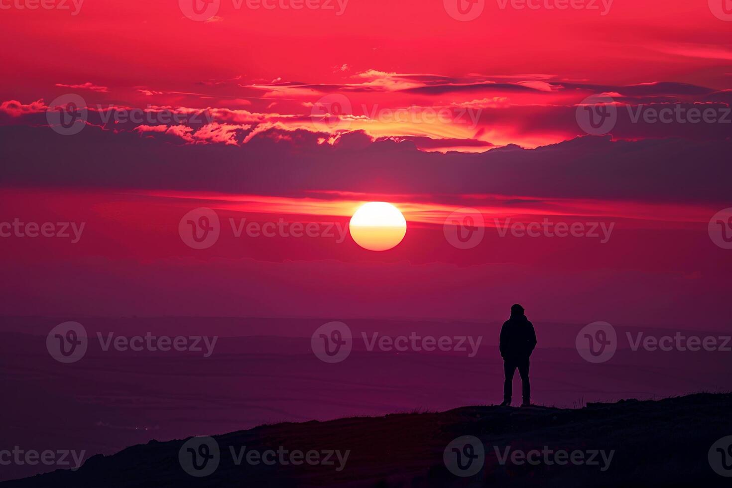 A person is standing on a hill and looking at the sun photo