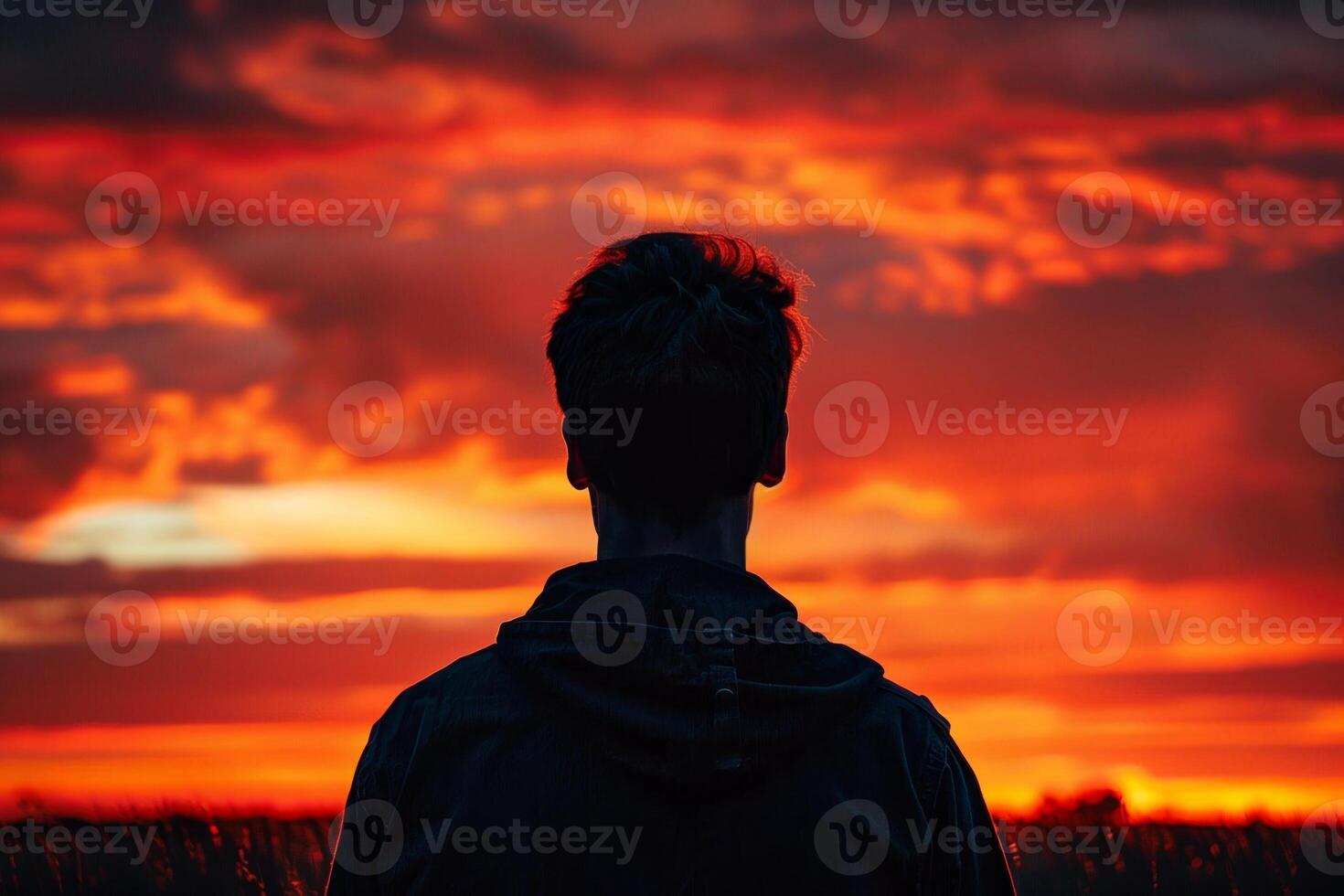 A man is standing in a field with a beautiful sunset in the background photo