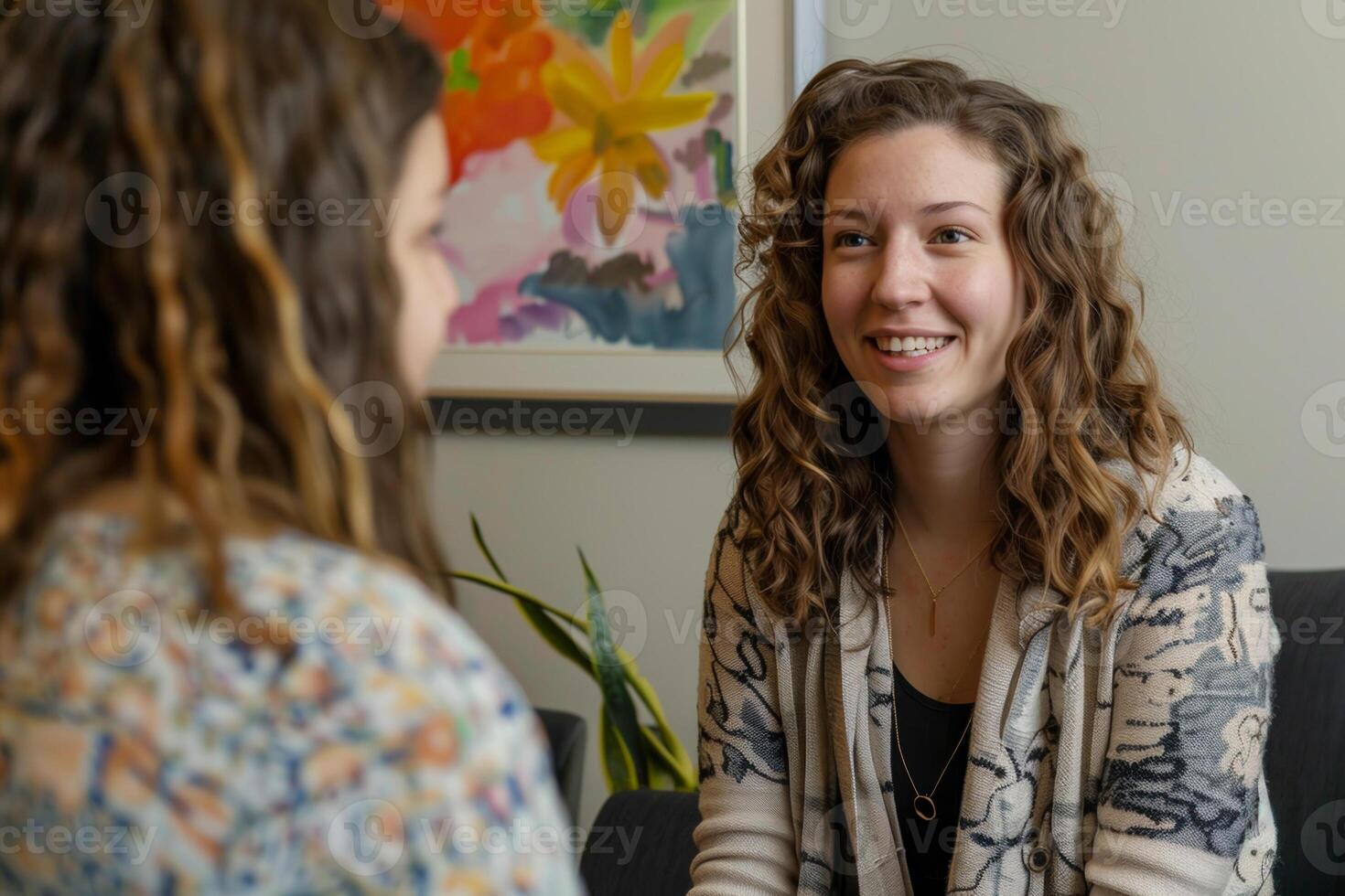 Two women sitting in a room talking to each other photo