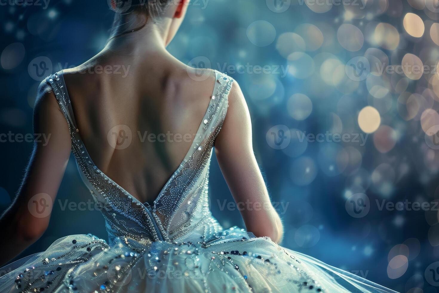 A dancer wearing a beautiful, shimmering gown sits in a graceful pose. The background features soft, blurred lights, creating a magical atmosphere photo