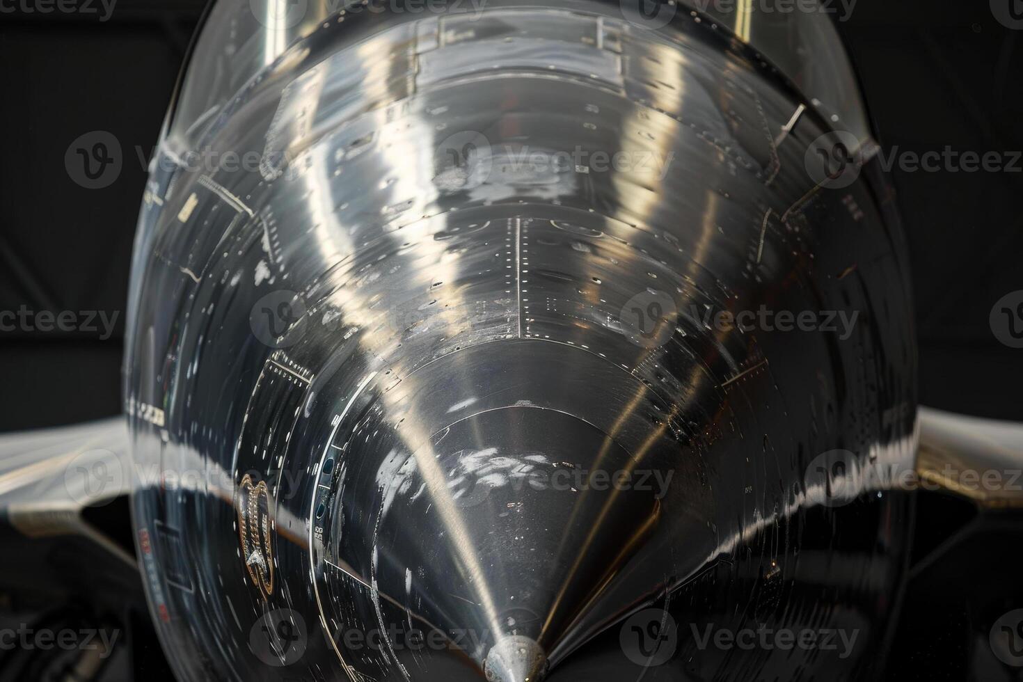 The polished nose of a jet aircraft gleams under the hangar lights, highlighting its aerodynamic design and detailed craftsmanship, emphasizing engineering precision photo