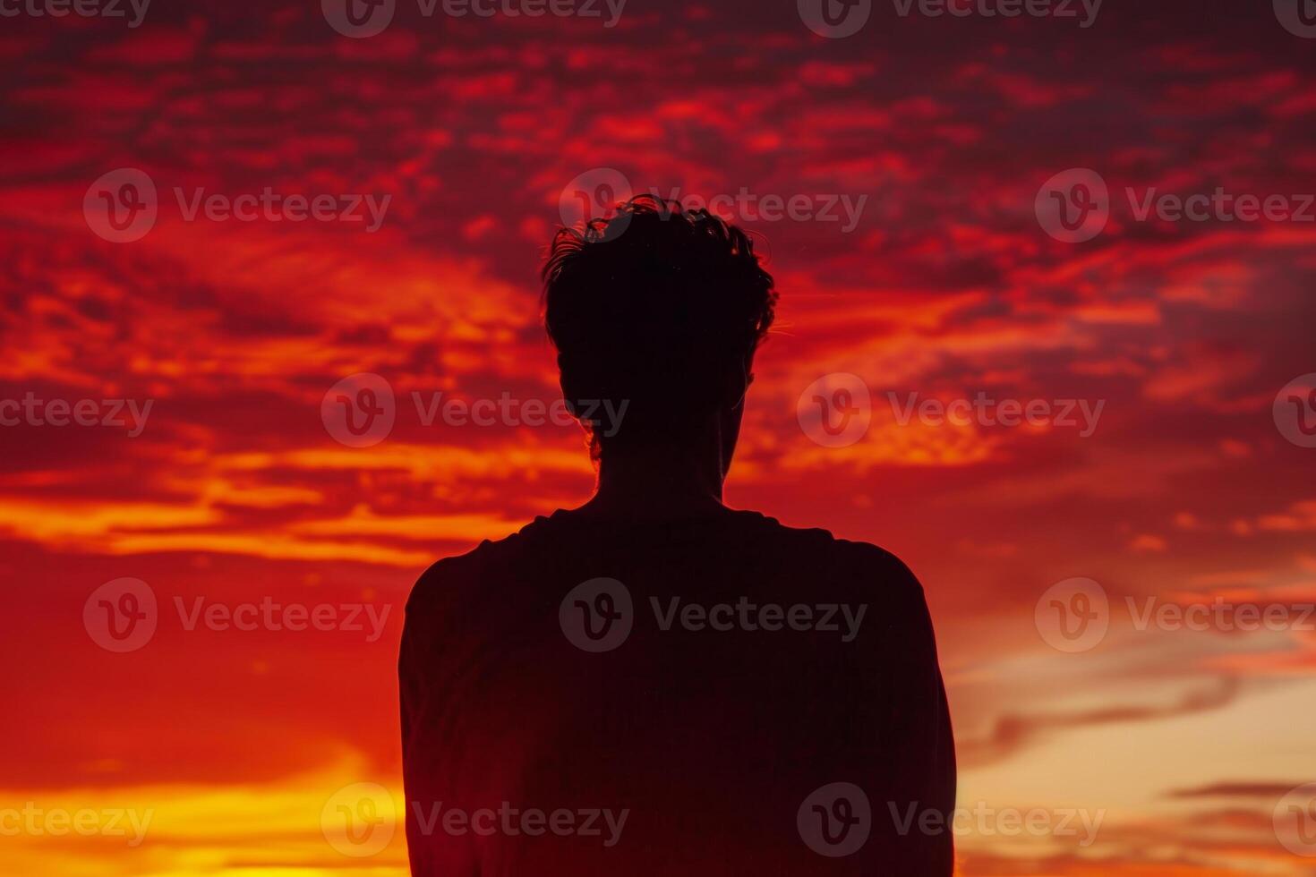 A man is standing in front of a beautiful sunset photo