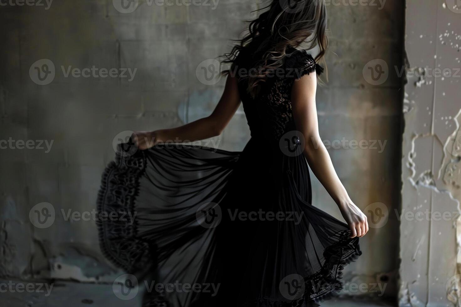 A woman gracefully twirls in a flowing black dress, her silhouette casting intriguing shadows in an empty, rustic indoor space illuminated by soft evening light photo