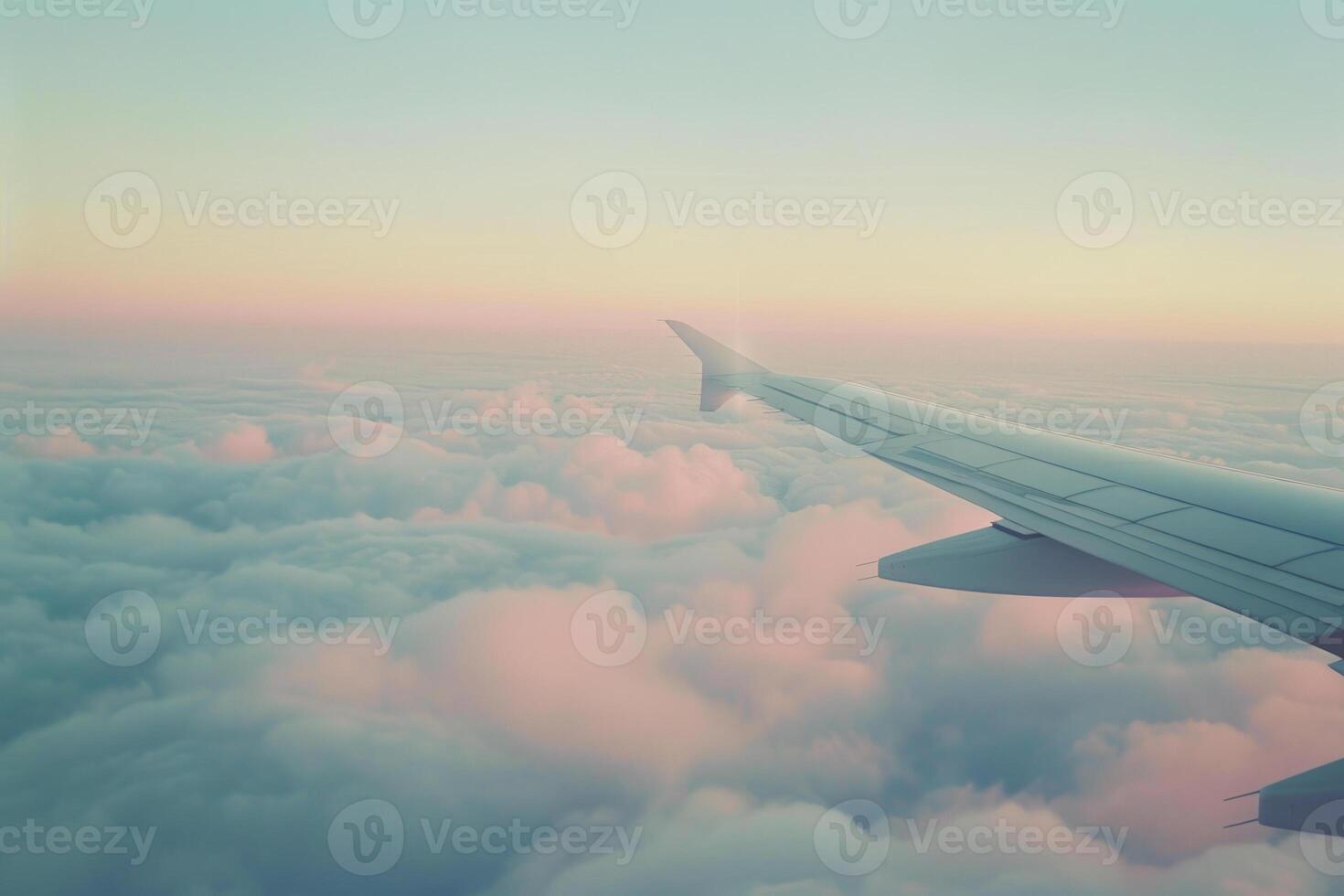 The airplane wing extends over billowing clouds, basking in soft pastel hues as the sun sets, creating a tranquil and serene atmosphere high above the earth photo