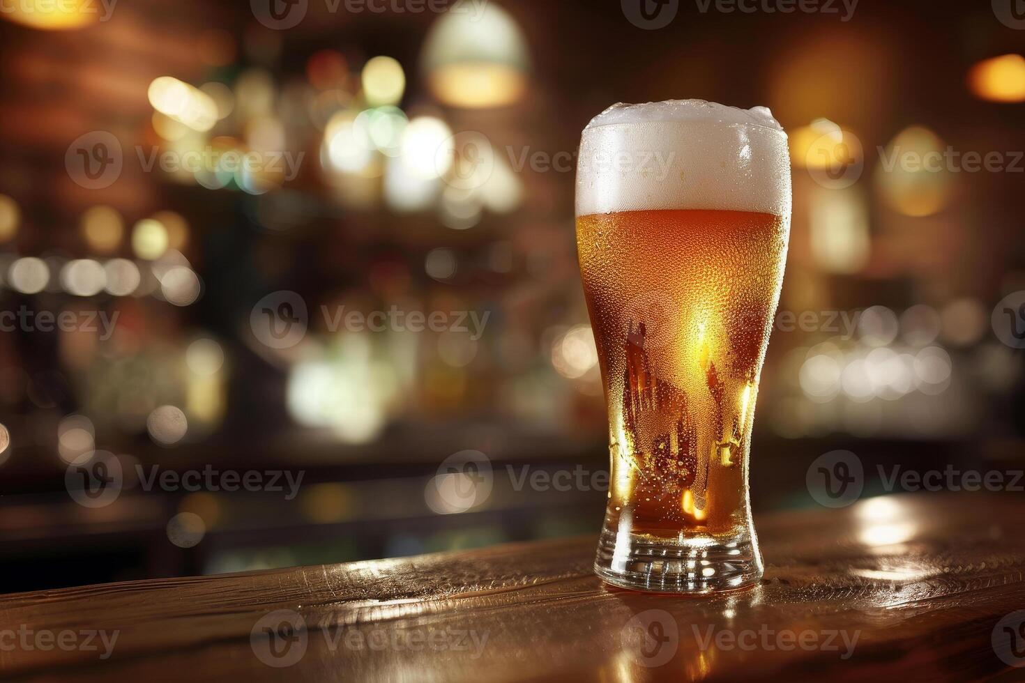 A cold, frothy glass of beer sits on a polished wooden bar top. The warm, inviting atmosphere of the pub glows in the background as evening unfolds photo