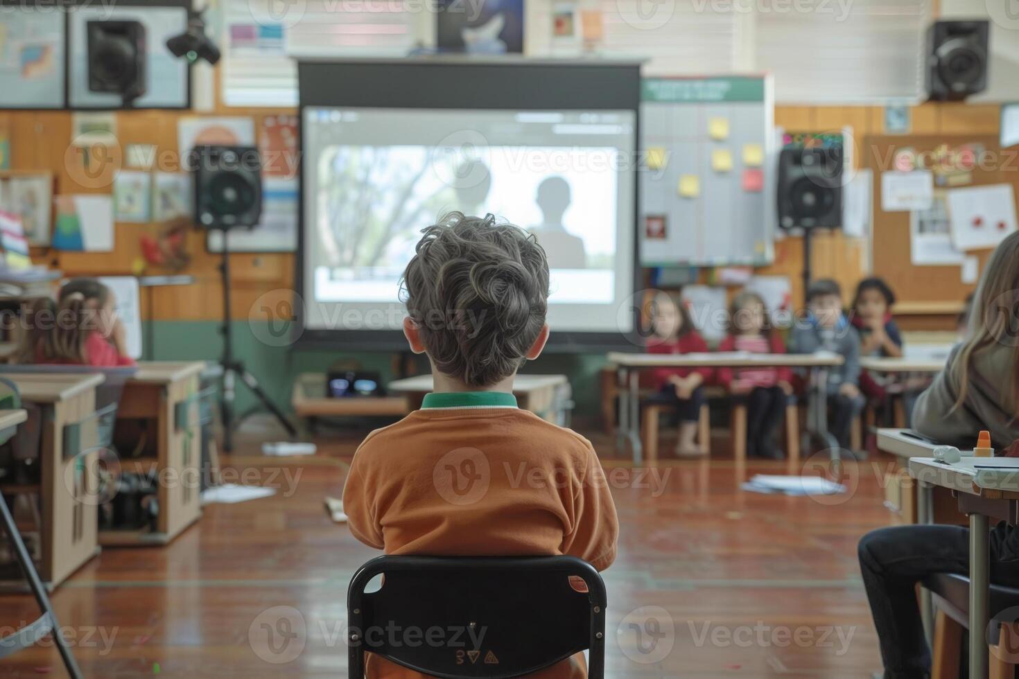 A child sitting in a chair in front of a classroom photo