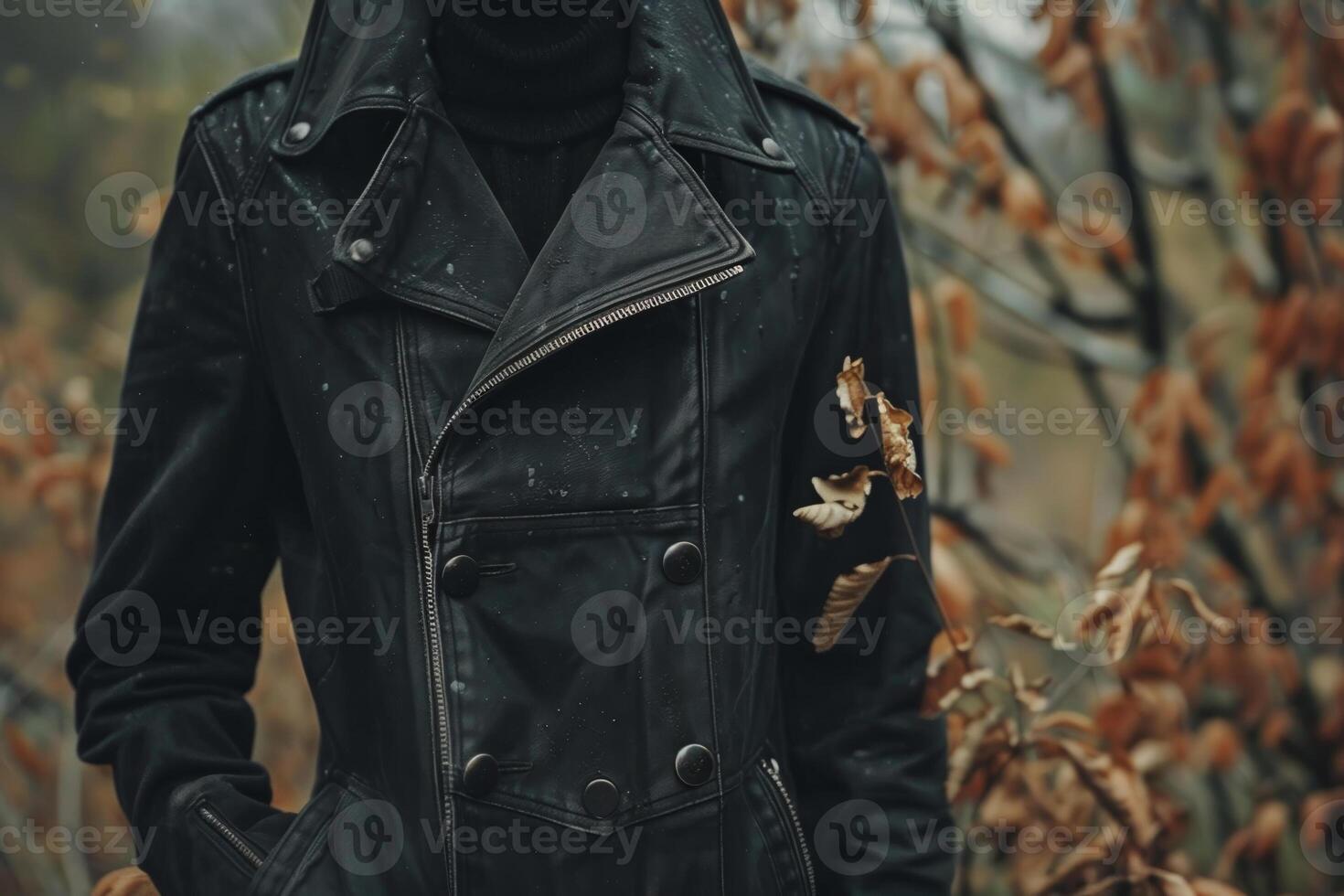 A figure wearing a black leather jacket poses confidently among dried leaves in an autumn landscape, capturing a moment of calm and reflection photo