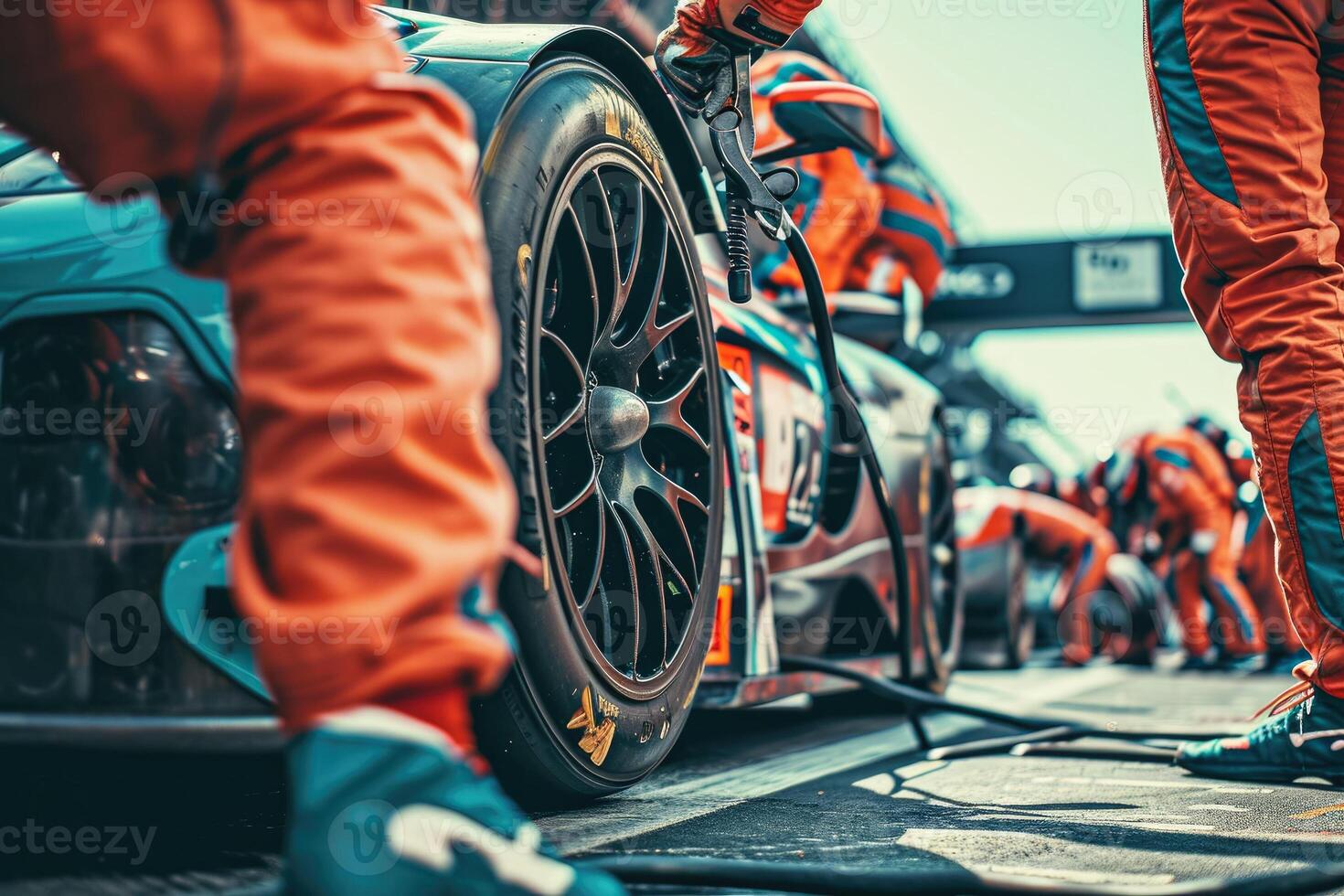 A group of people in orange uniforms are working on a race car photo
