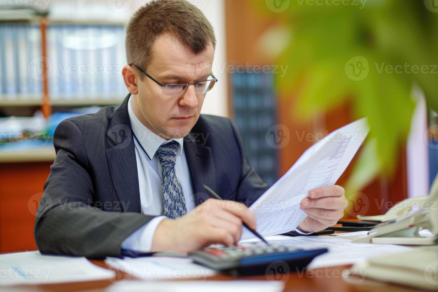 A man in a suit and tie is looking at a piece of paper photo