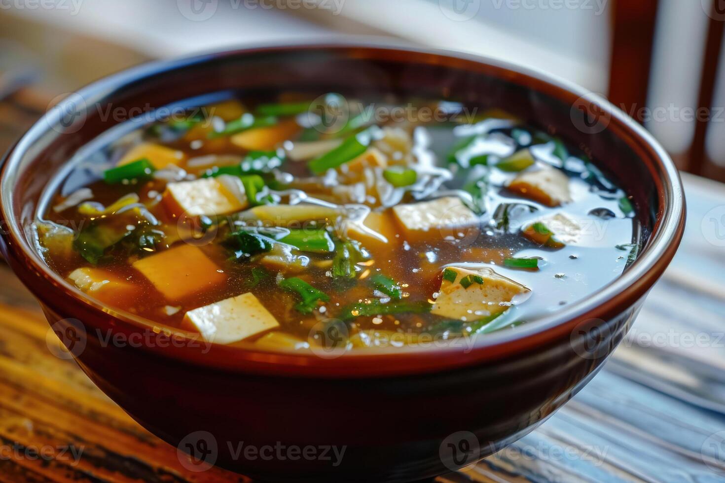 A bowl of soup with tofu and greens in it photo