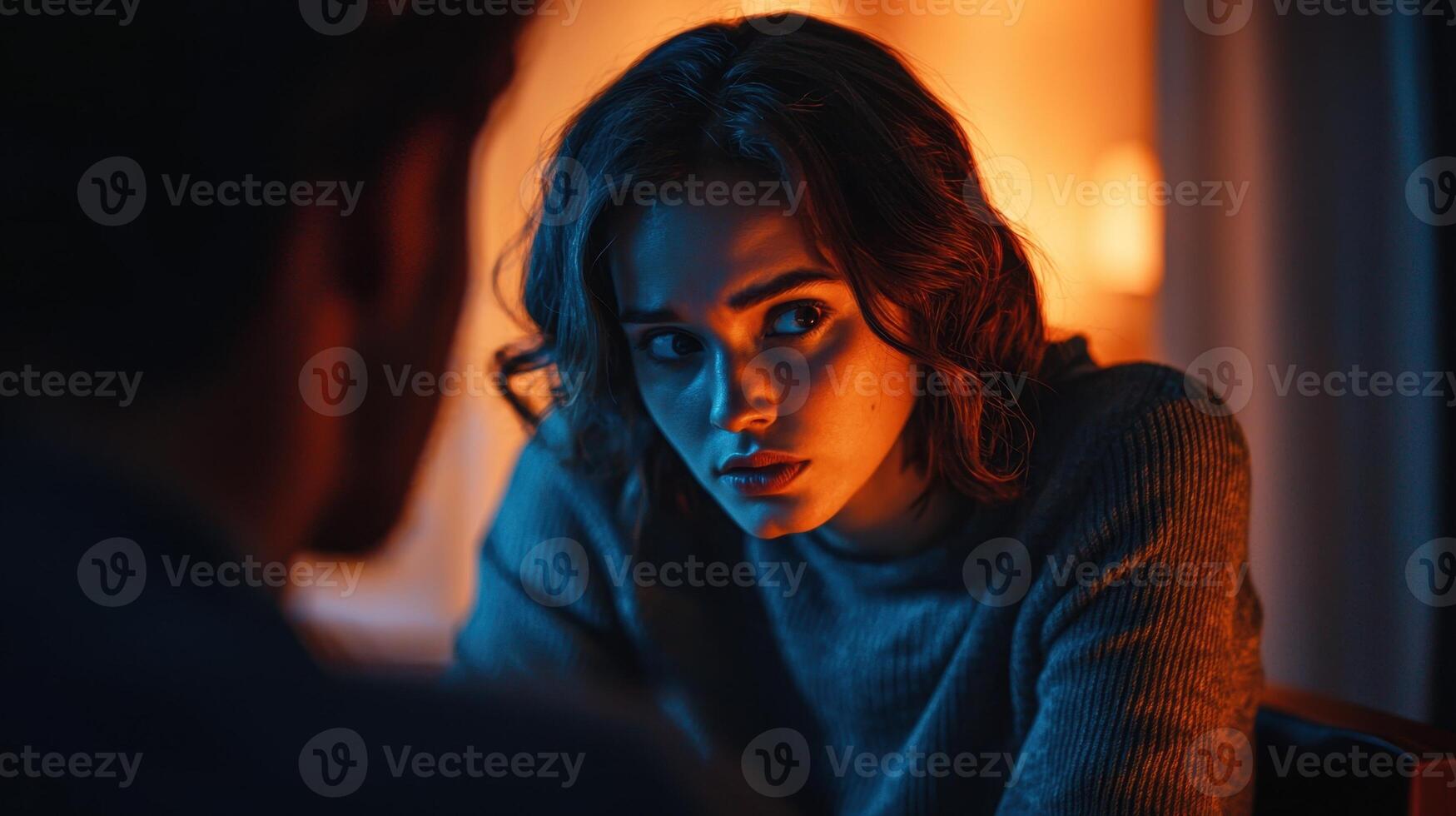 A woman is looking at a man in a dimly lit room photo