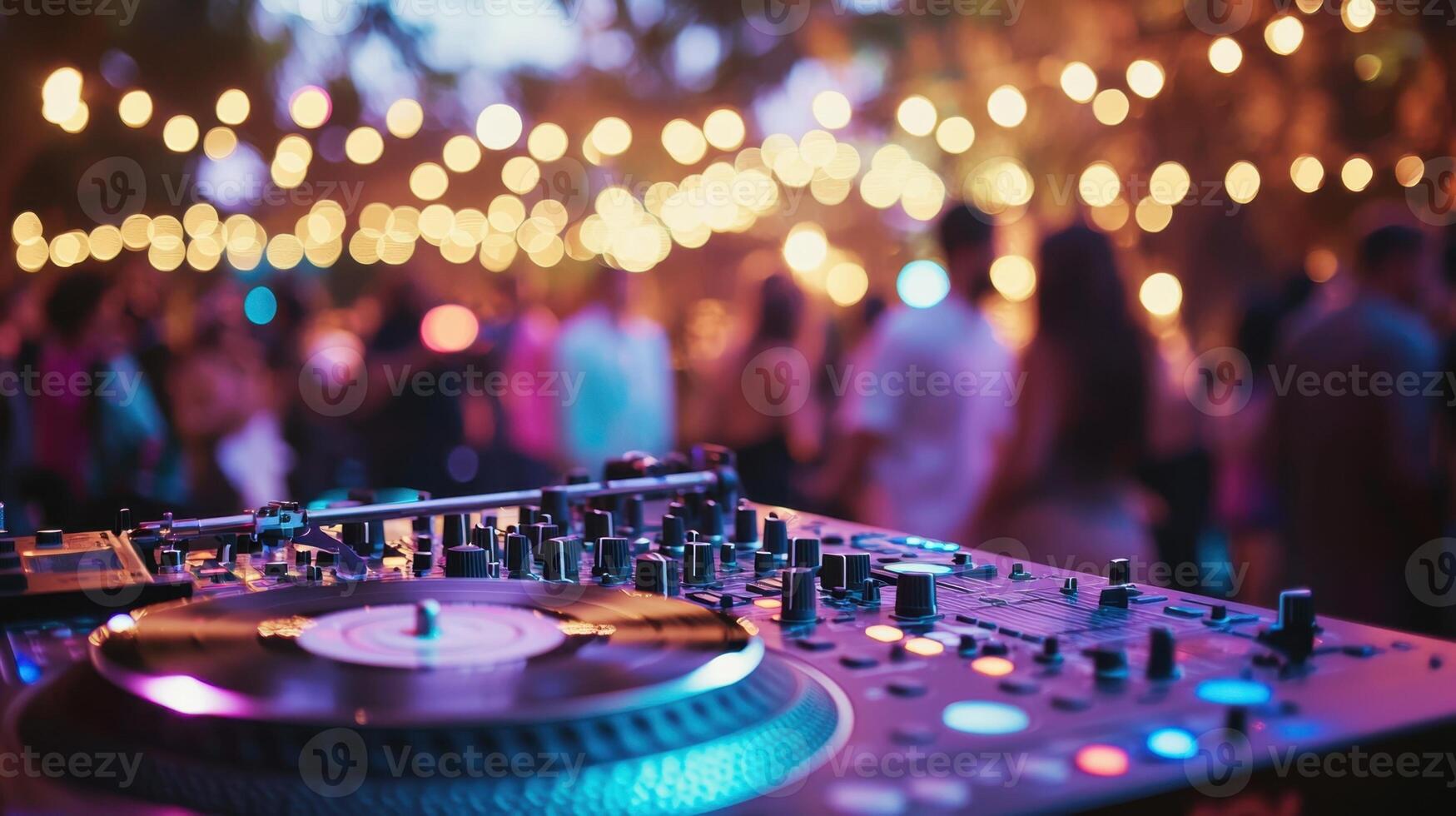 A lively outdoor event showcases a DJ console with records spinning, surrounded by colorful lights and guests dancing, creating an energetic evening atmosphere photo