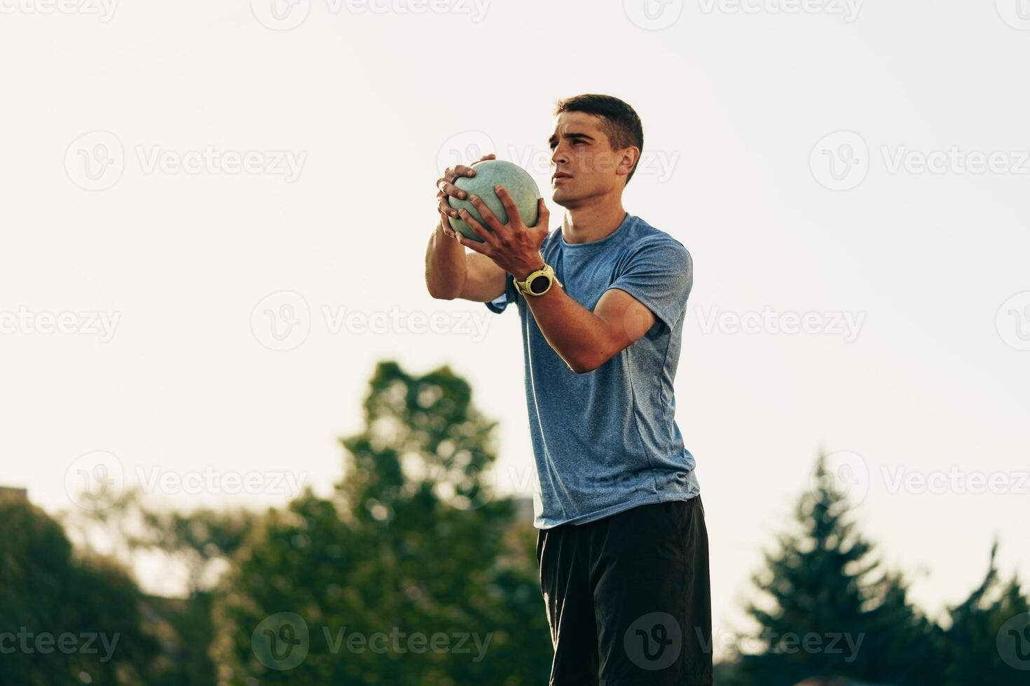 Athlete practicing throw with a weighted ball during outdoor training session in the evening light photo