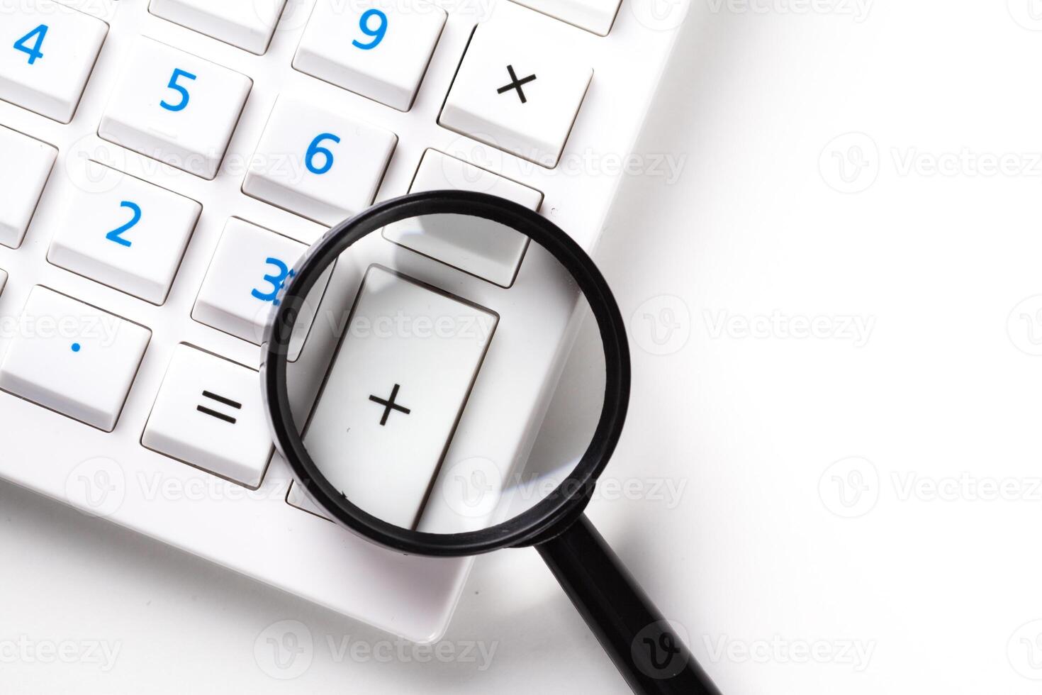 Calculator with a magnifying glass on a white background photo