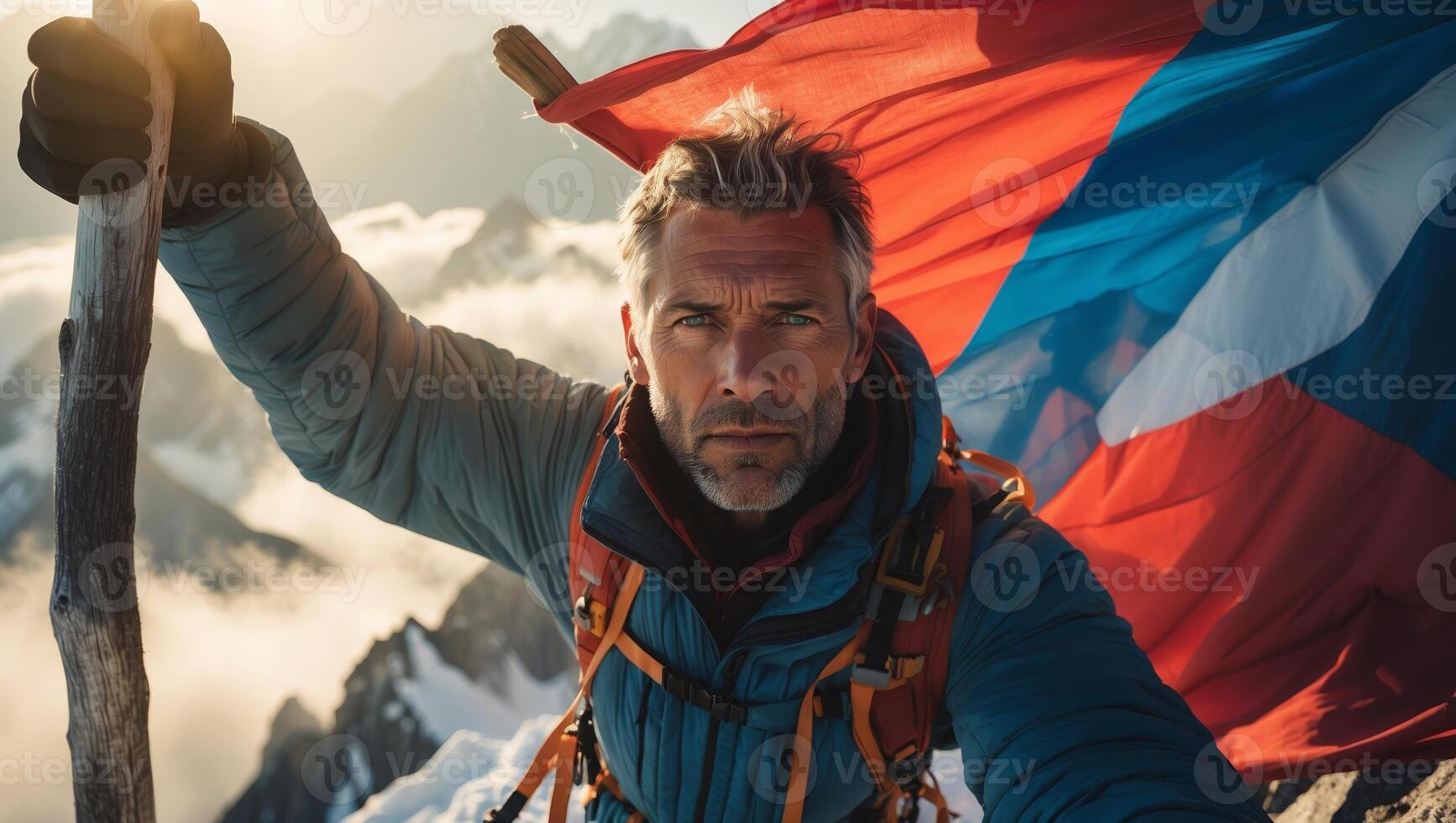Climber celebrates summit achievement with flag and stunning mountain backdrop during sunset photo