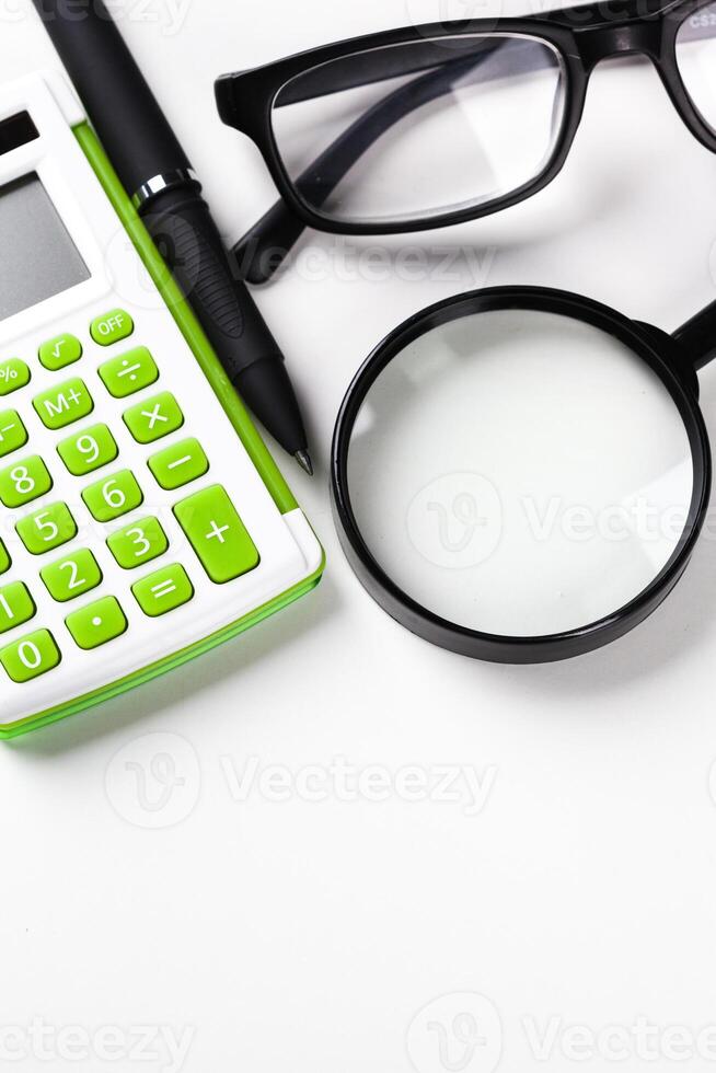 Calculator with a magnifying glass on a white background photo